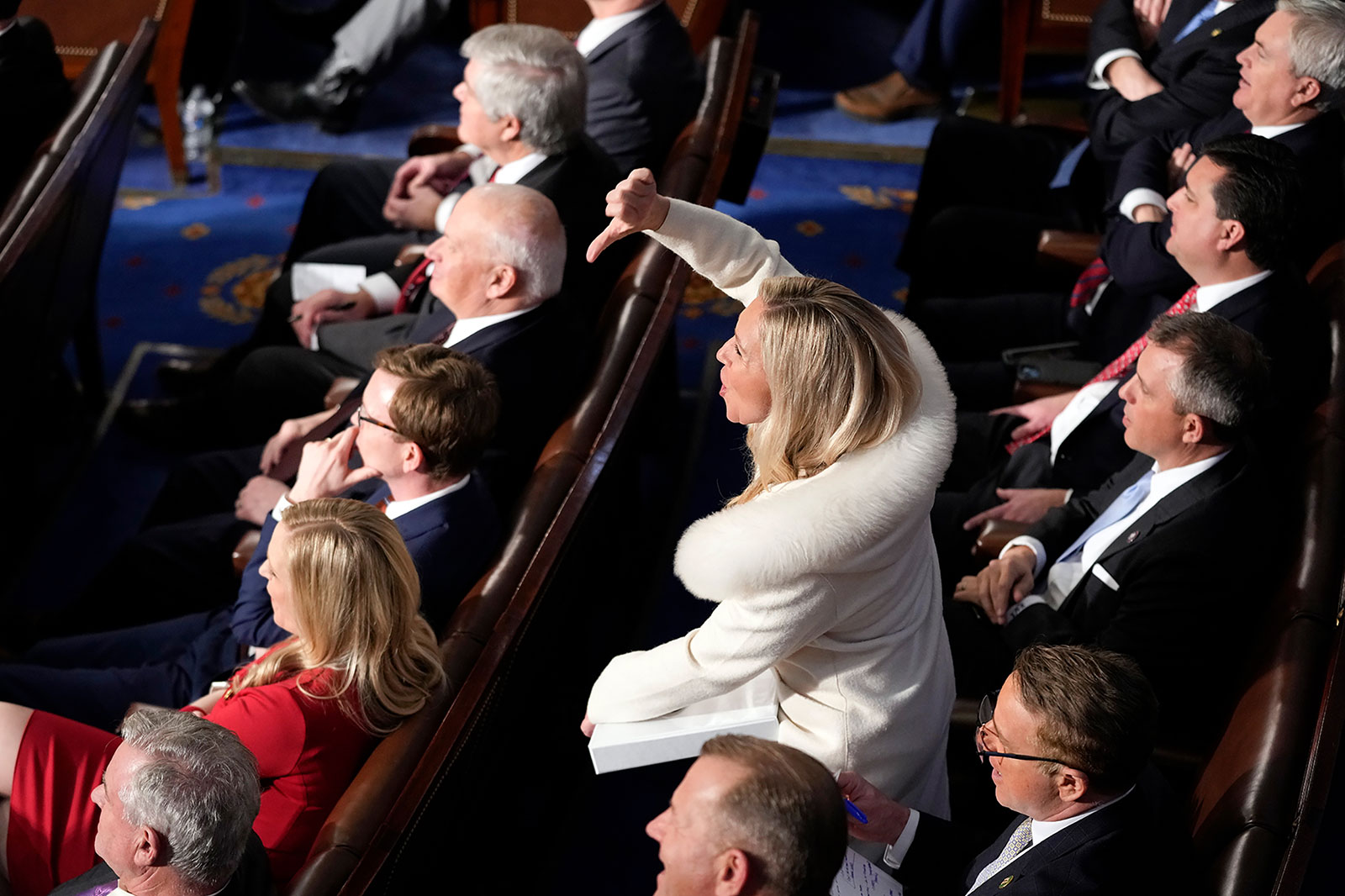 Rep. Marjorie Taylor Greene makes a thumbs down gesture as Biden speaks.