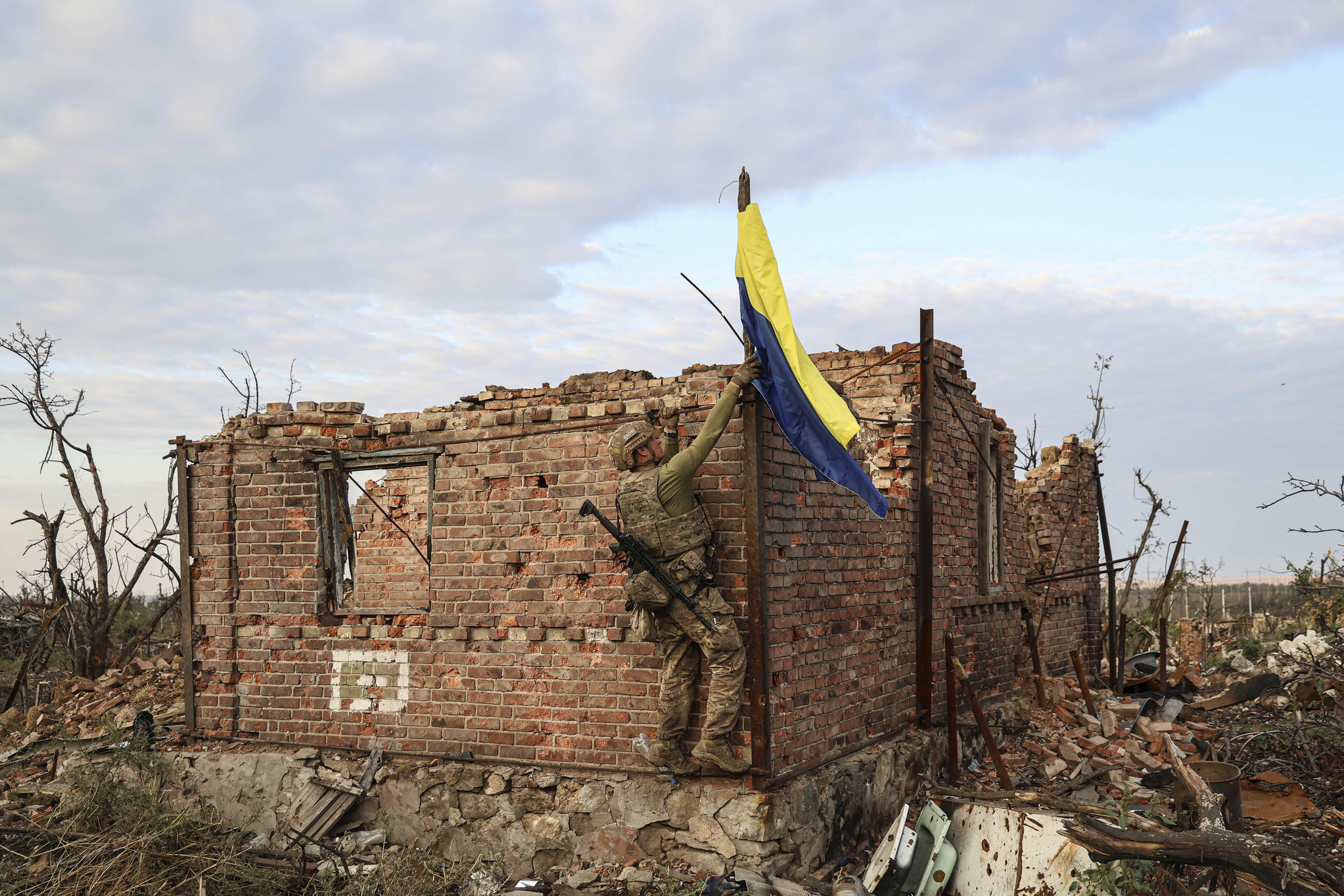 A commander of Ukraine's 3rd Assault Brigade raises his country's flag in the frontline village of Andriivka, Ukraine, on September 16.