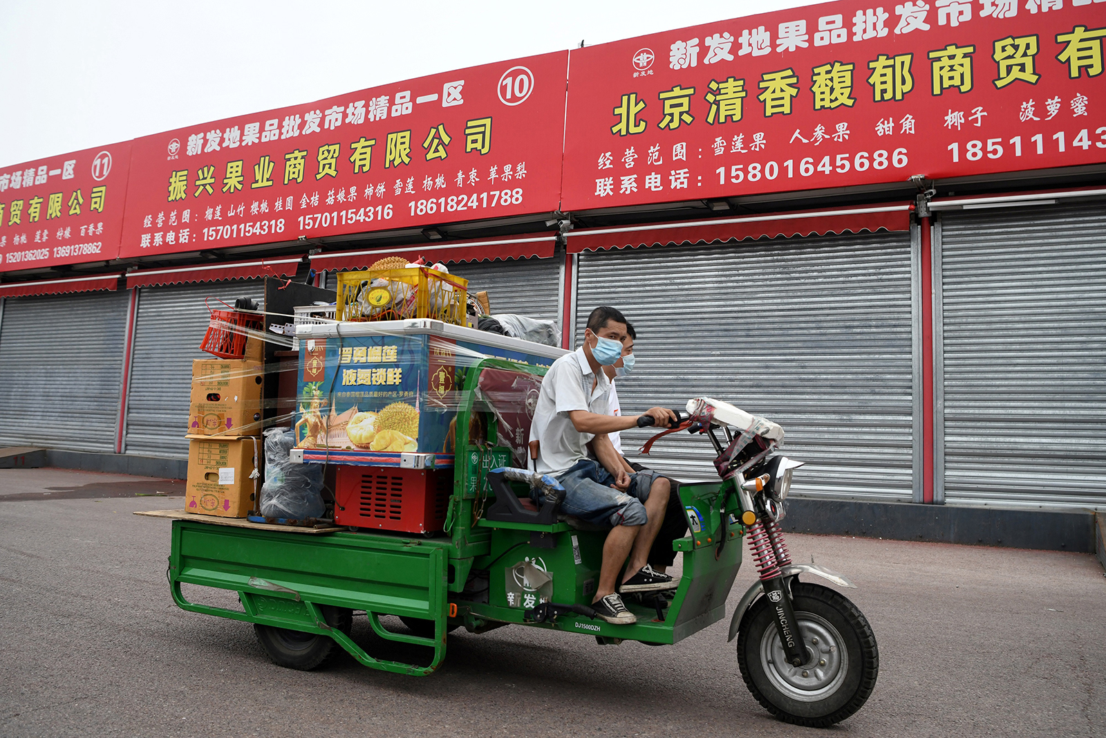 Workers drive a motorized tricycle carrying merchandise at the Xinfadi wholesale market in Beijing on August 5.