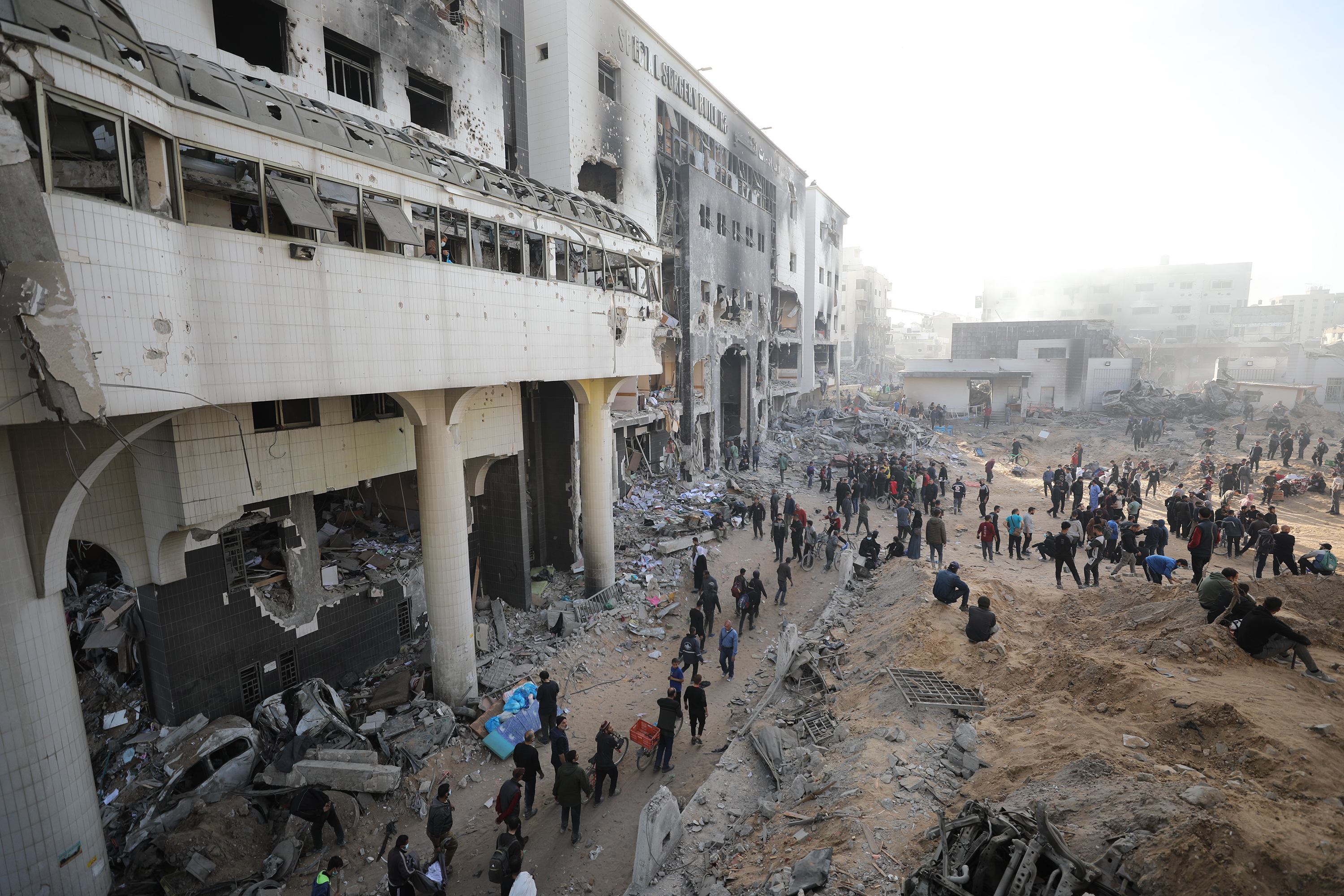 People walk among the damaged buildings where Al-Shifa Hospital and its surrounding are located in Gaza City, on April 1.