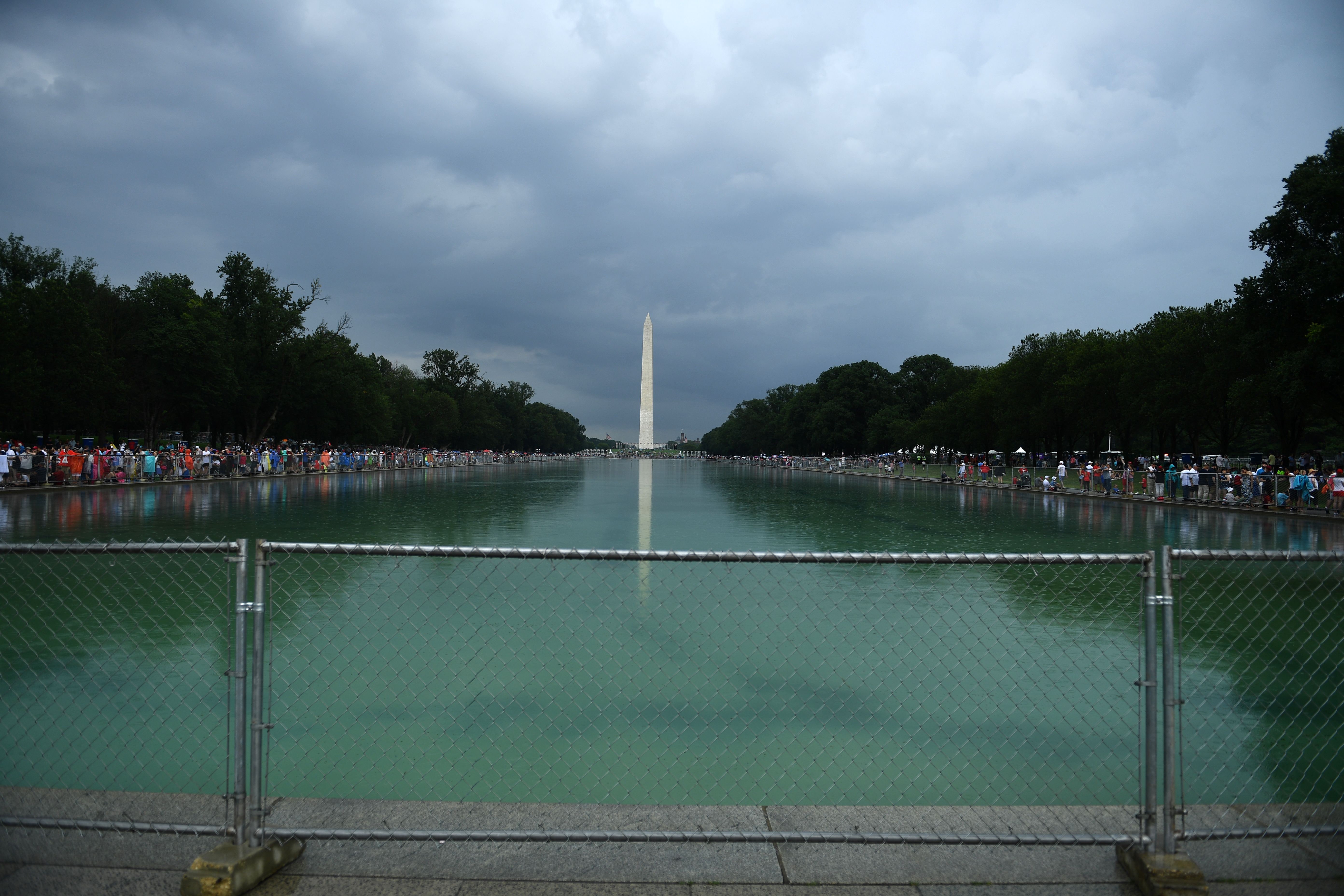 People gather under rain on the National Mall ahead of the "Salute to America" event at the Lincoln Memorial in Washington, DC, on July 4, 2019.