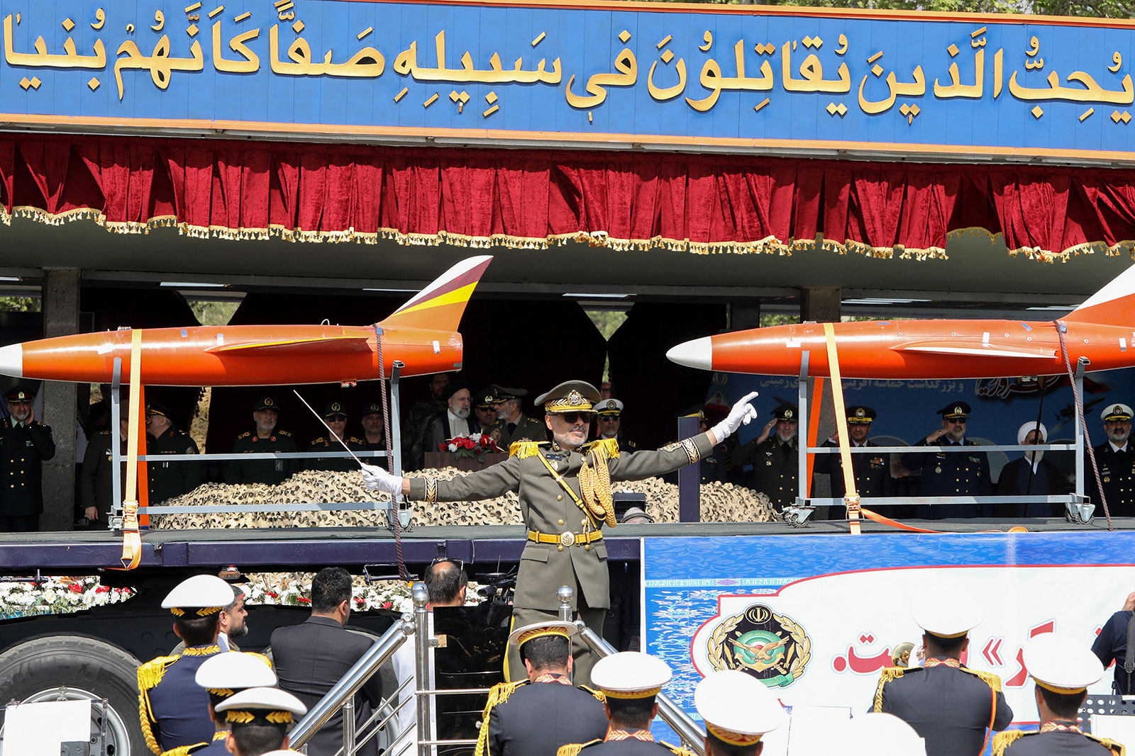 A member of the Iranian armed forces directs an army orchestra as a truck carries drones during a military parade in Tehran on April 17. 