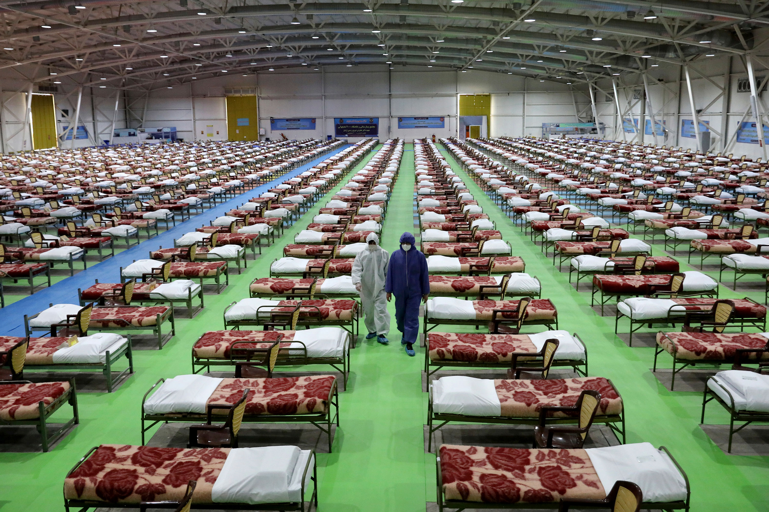 People in protective clothing walk past rows of beds at a temporary 2,000-bed hospital set up by the Iranian army at an international exhibition center in Tehran, Iran, on March 26.