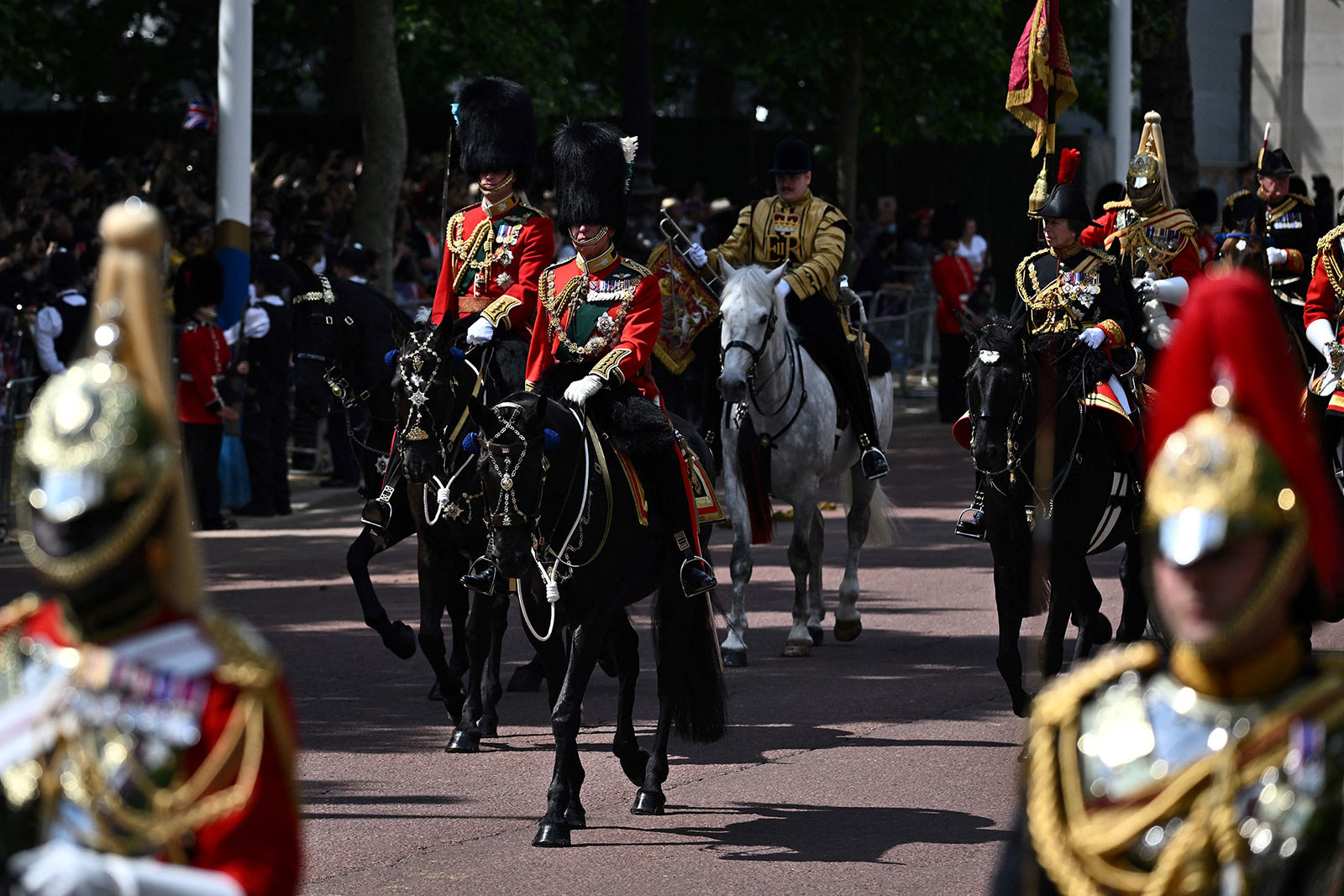 Britain's Prince Charles, center, in his role as Colonel of the Welsh Guards, Britain's Prince William, left, in his role as Colonel of the Irish Guards, and Britain's Princess Anne, right, in her role as Colonel of the Blues and Royals, ride their horses along The Mall during the Trooping the Colour.