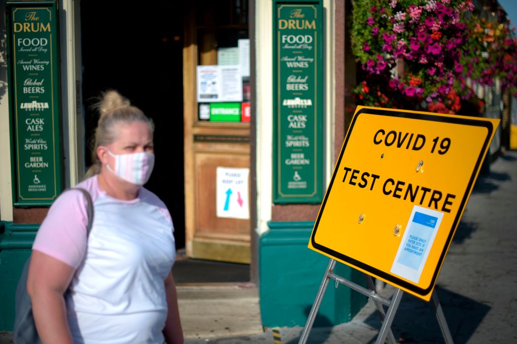 Pedestrians walk past a sign for a Covid-19 test centre in Leyton, east London on September 19.