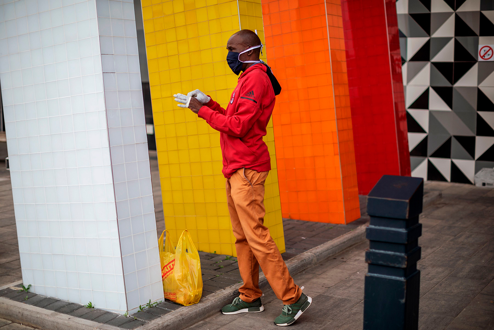 A man wearing a face mask puts on a pair of gloves at the entrance of a shopping mall in Alexandra, Johannesburg, South Africa on April 10.