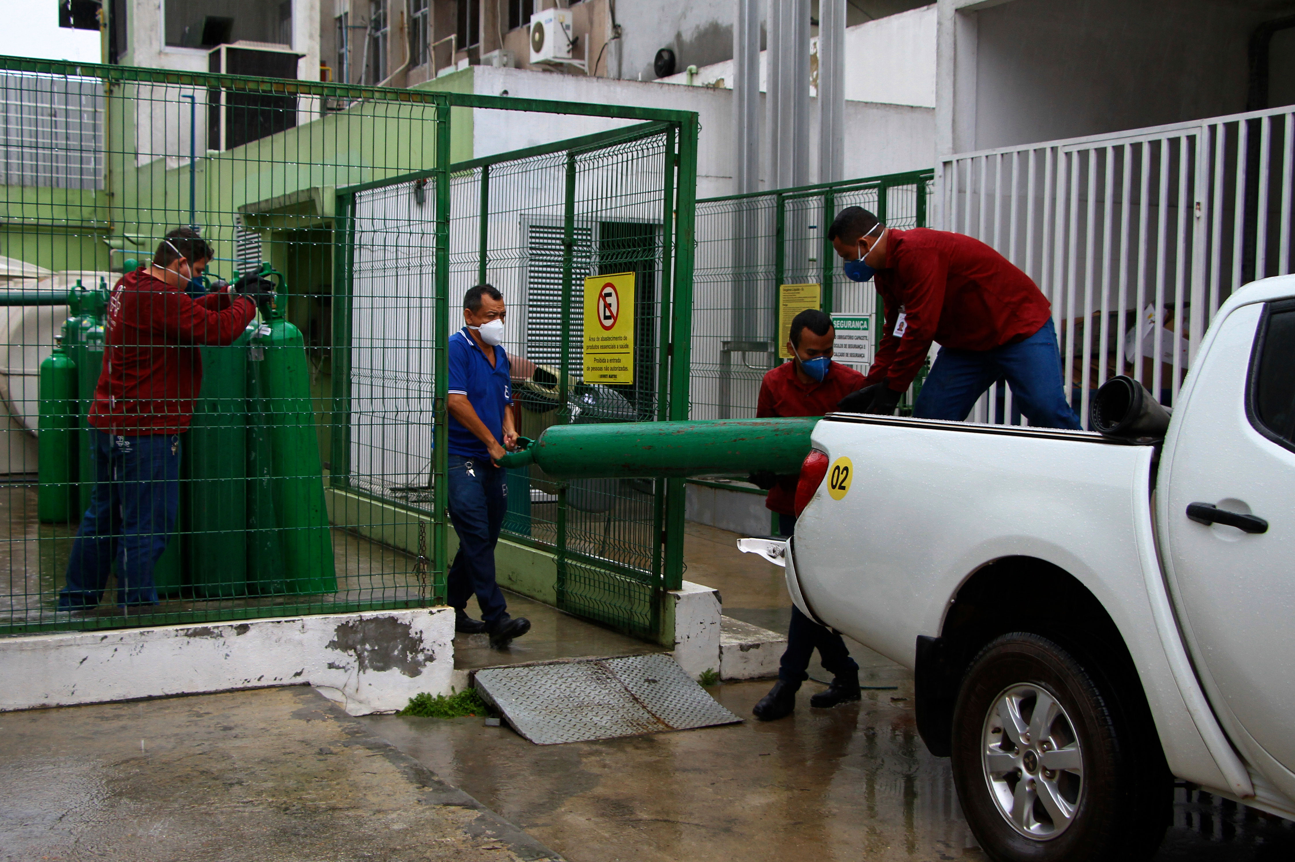 Workers carry empty oxygen tanks at Getulio Vargas Hospital in Manaus, Brazil, on January 14.