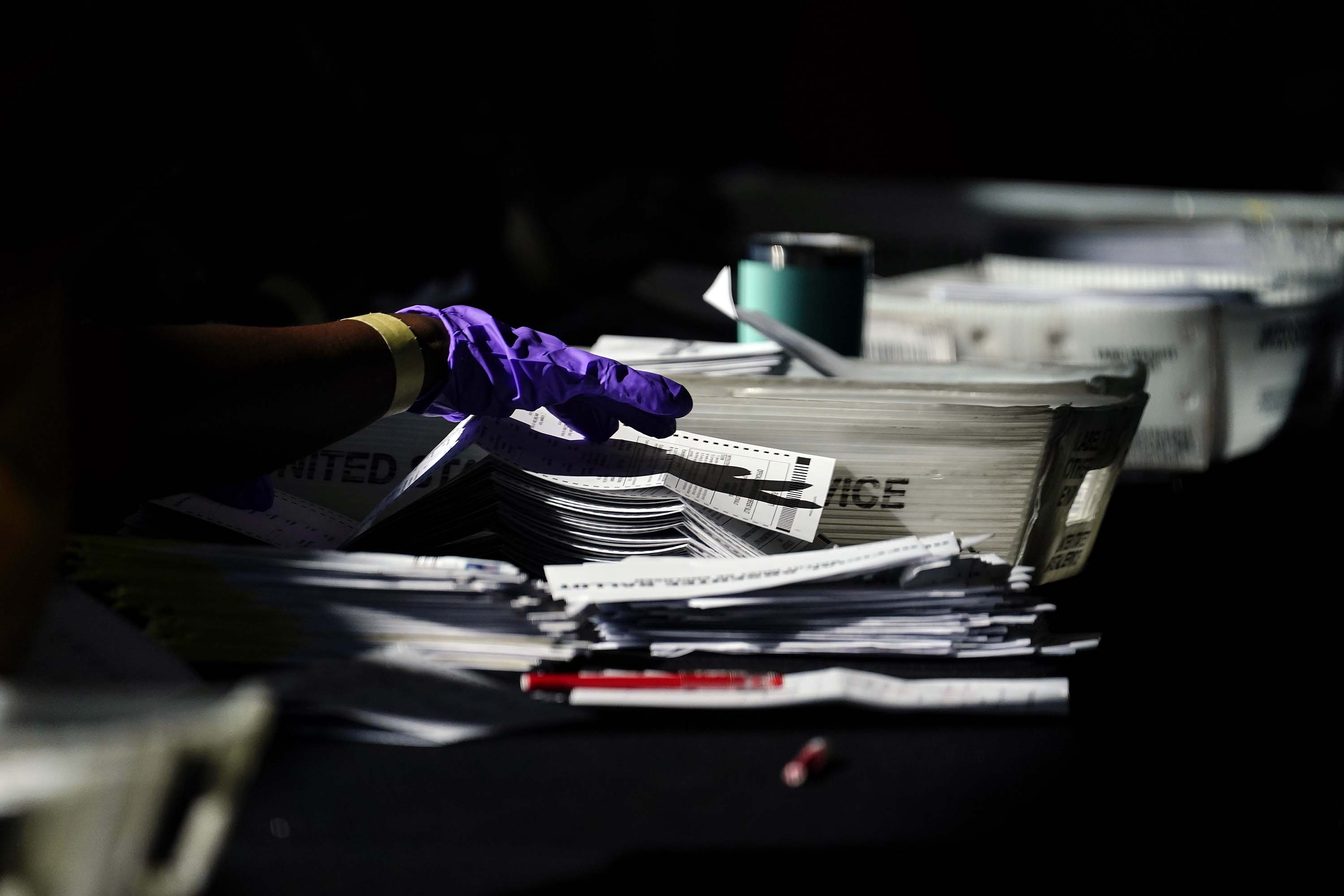 Election personnel handle ballots as vote counting in the general election continues at State Farm Arena in Atlanta, Georgia, on Wednesday, November 4. 