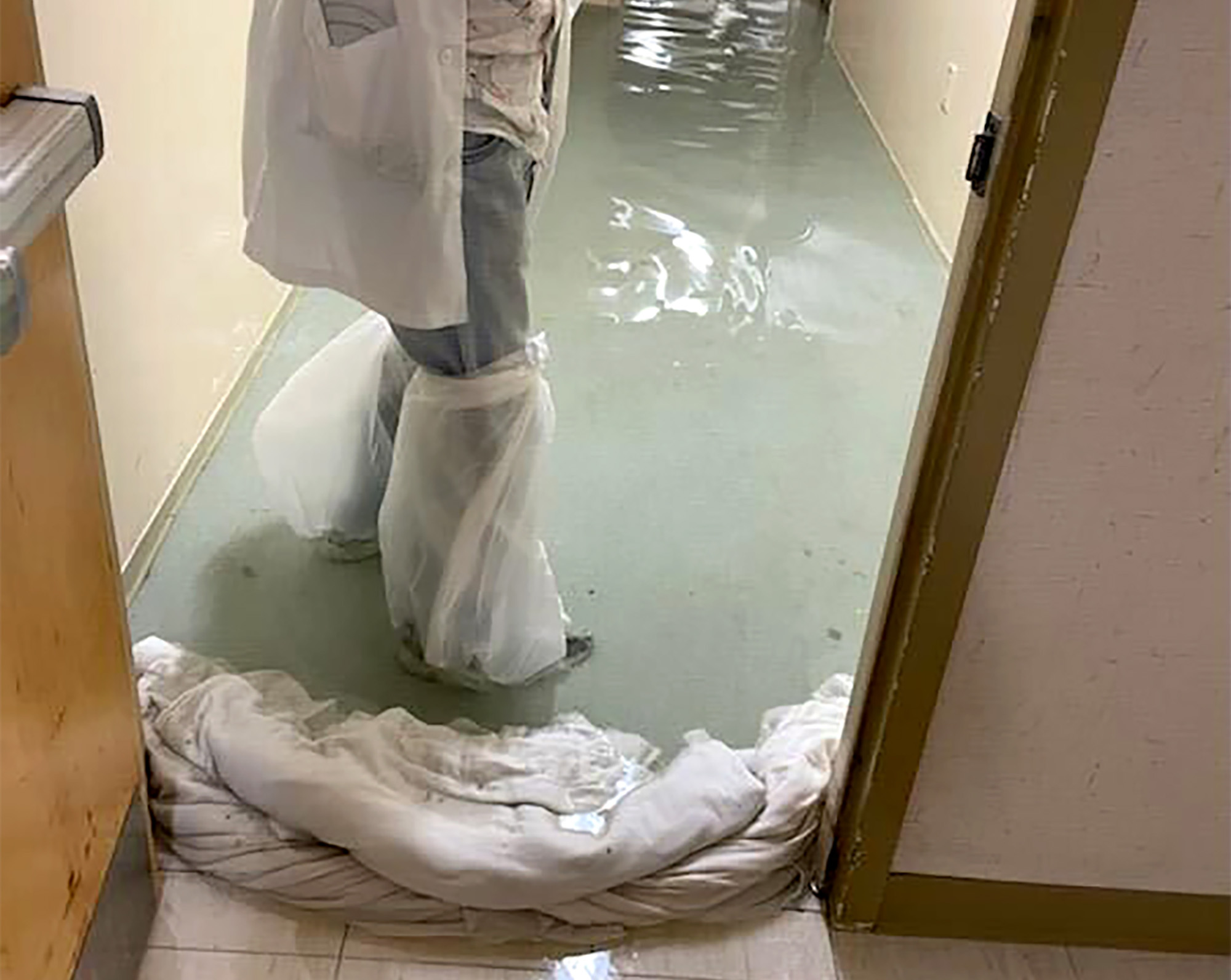 In a photo provided by Dr. Birgit Bodine shows a staff member standing in a flooded hallway at HCA Florida Fawcett Hospital in Port Charlotte, Fla., Wednesday, Sept. 28.