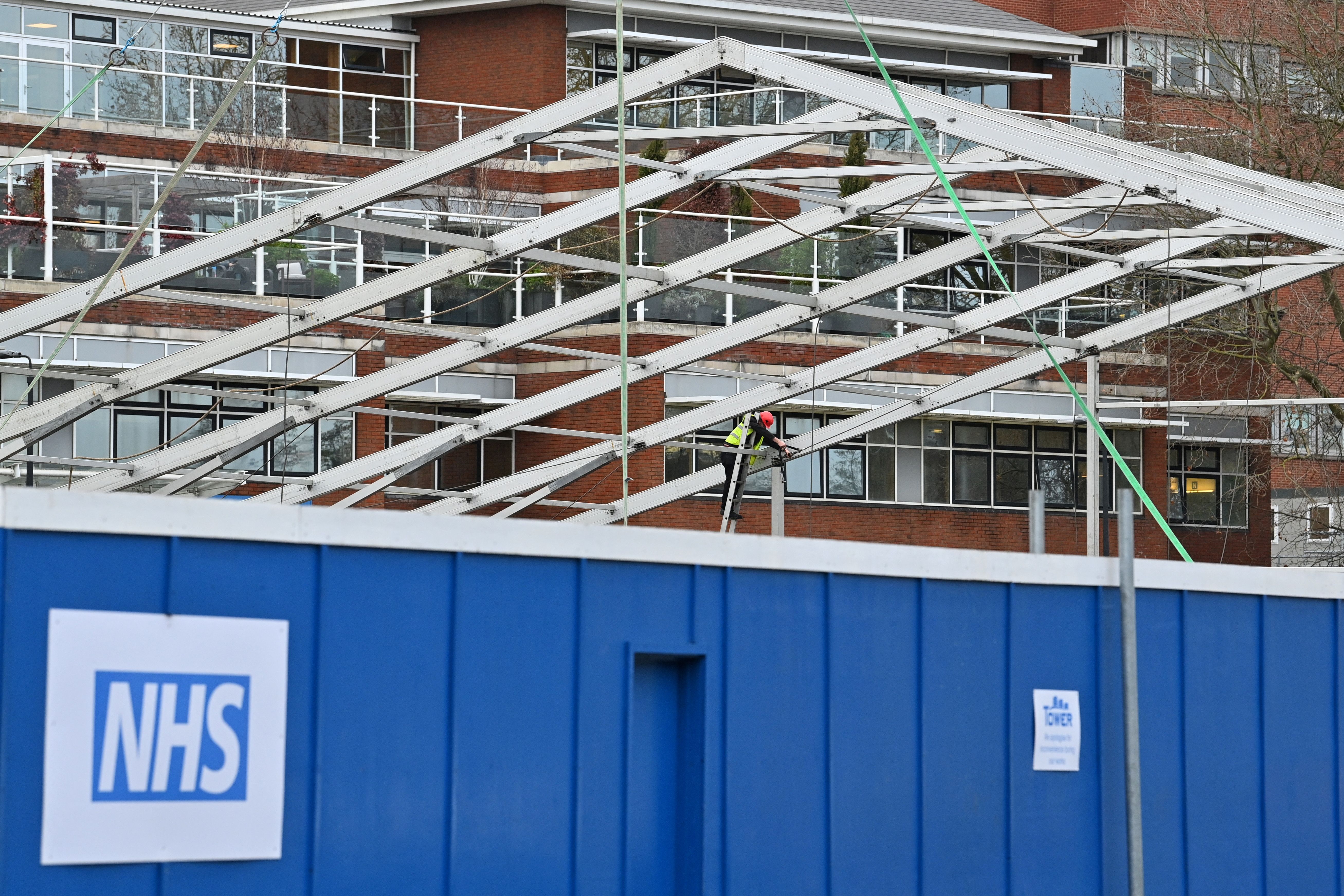 A member of a construction team works on the erection of a temporary field hospital in the grounds of St George's Hospital in Tooting, south London on December 30, 2021, as the number of daily Covid-19 cases has increased, fuelled by the highly contagious Omicron variant. - England is set to open temporary field hospitals to contain a possible overspill of inpatients due to a surge in coronavirus cases, the national health service said Thursday. 