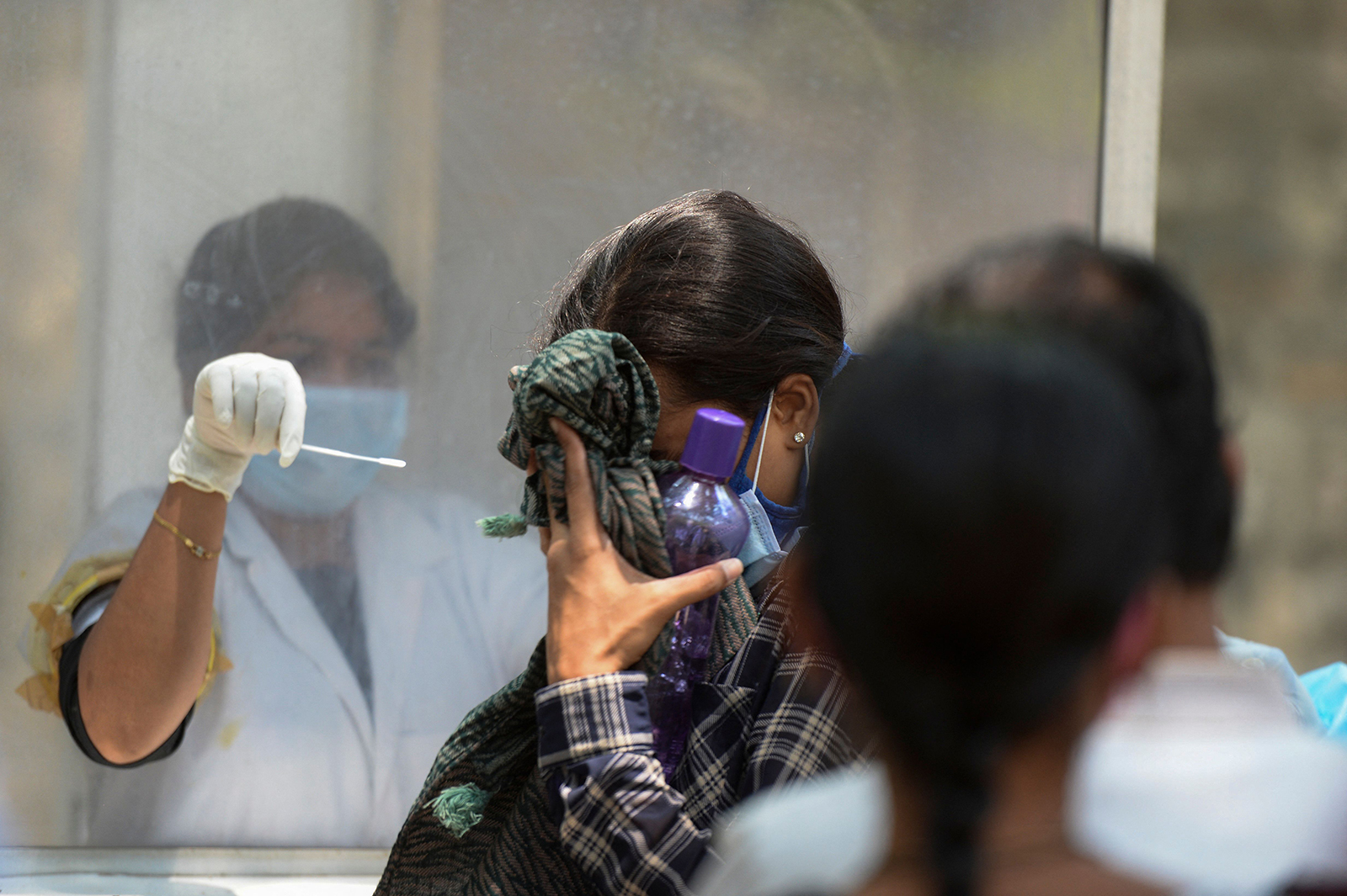 A woman reacts as a health worker prepares to collect a nasal swab sample to test for Covid-19 at a primary health center, in Hyderabad, India, on May 3.