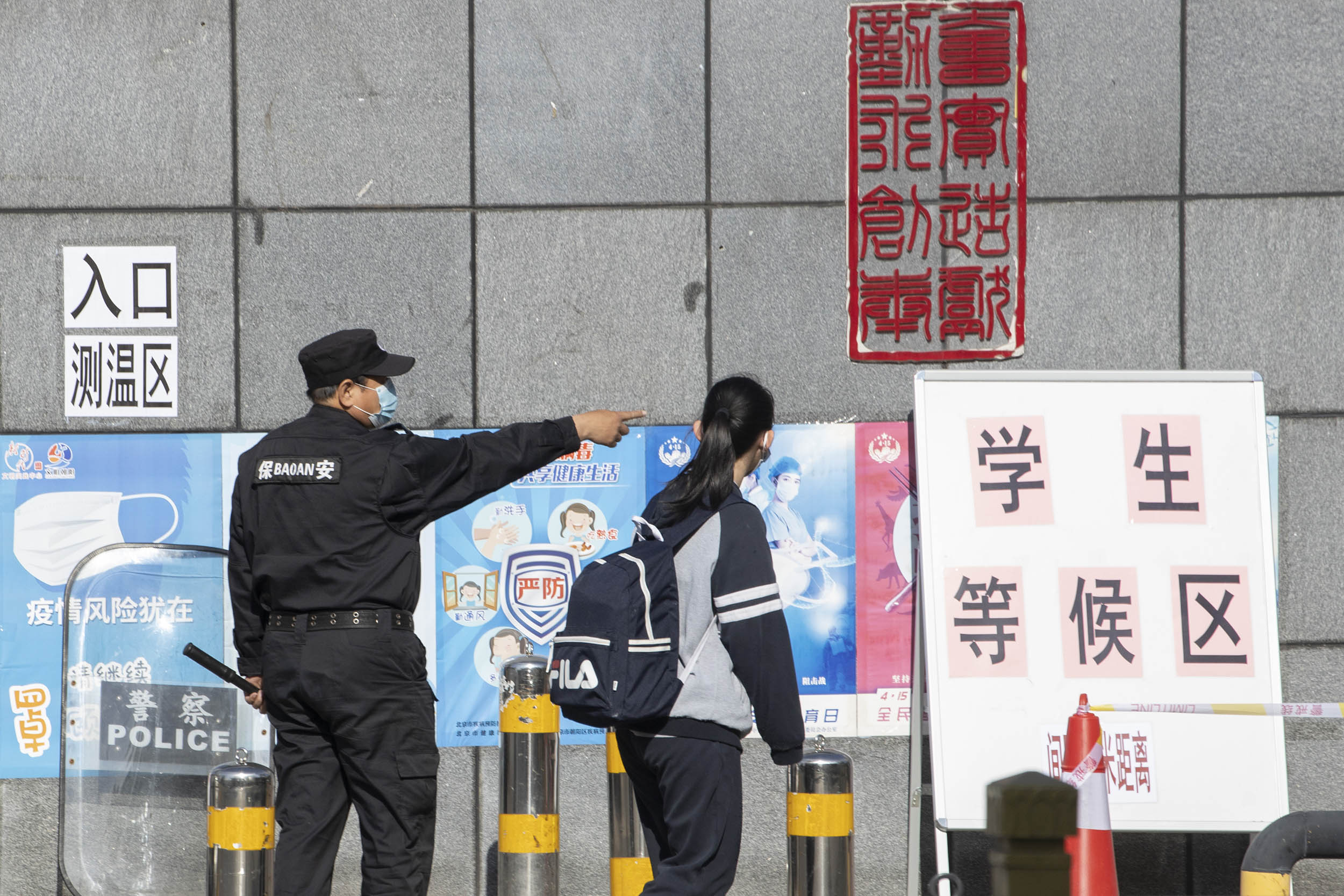 A security guard directs a student near a sign reading "Waiting Zone for Students " during the reopening of school in Beijing, China, on May 11. 