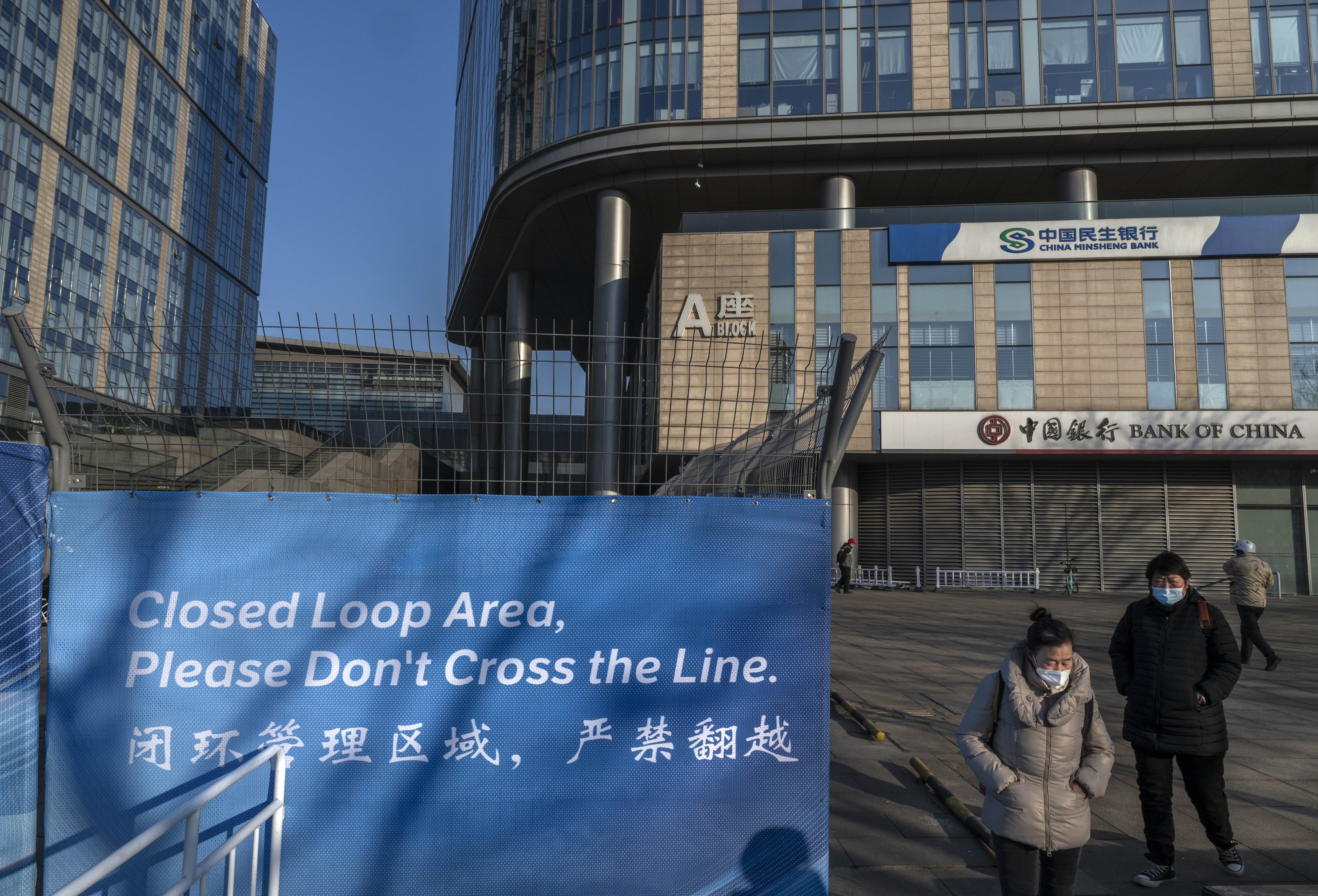 People walk outside the "closed-loop" where a number of Winter Olympics venues are located on Saturday in Beijing. 