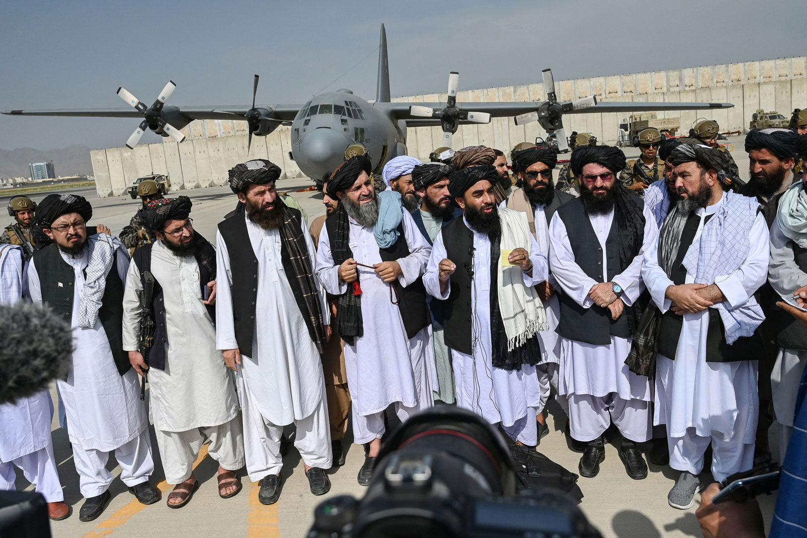 Taliban spokesman Zabihullah Mujahid, center, with shawl, speaks to the media at the airport in Kabul on August 31.