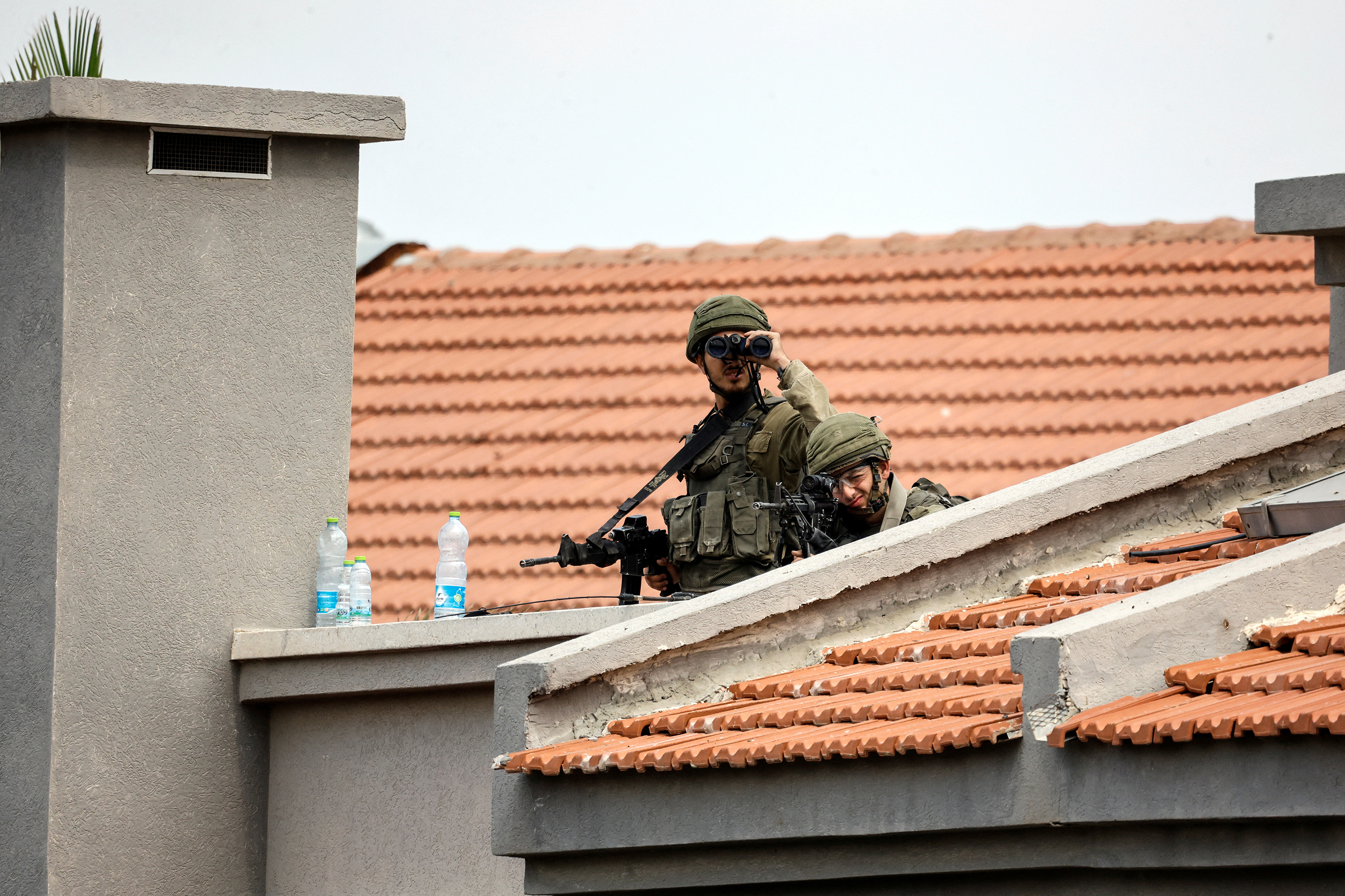 Israeli soldiers look out as they stand between buildings in Sderot, southern Israel, on October 9, 2023.