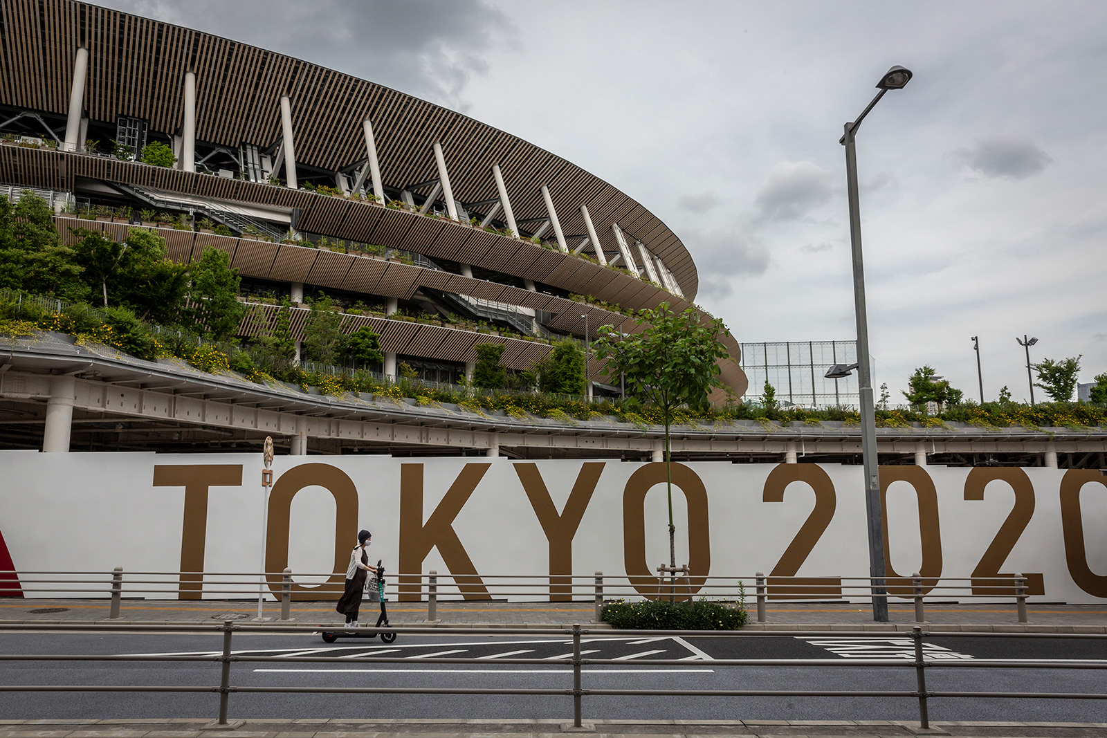 A woman drives an electric scooter in front of the New National Stadium, the main stadium for the Tokyo Olympics, on June 3 in Tokyo.