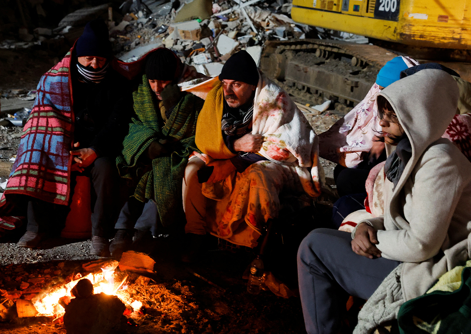 People rescued by rsecue group ISAR Germany,  wait by a fire during the rescue operation in Kirikhan, Turkey on February 10. 