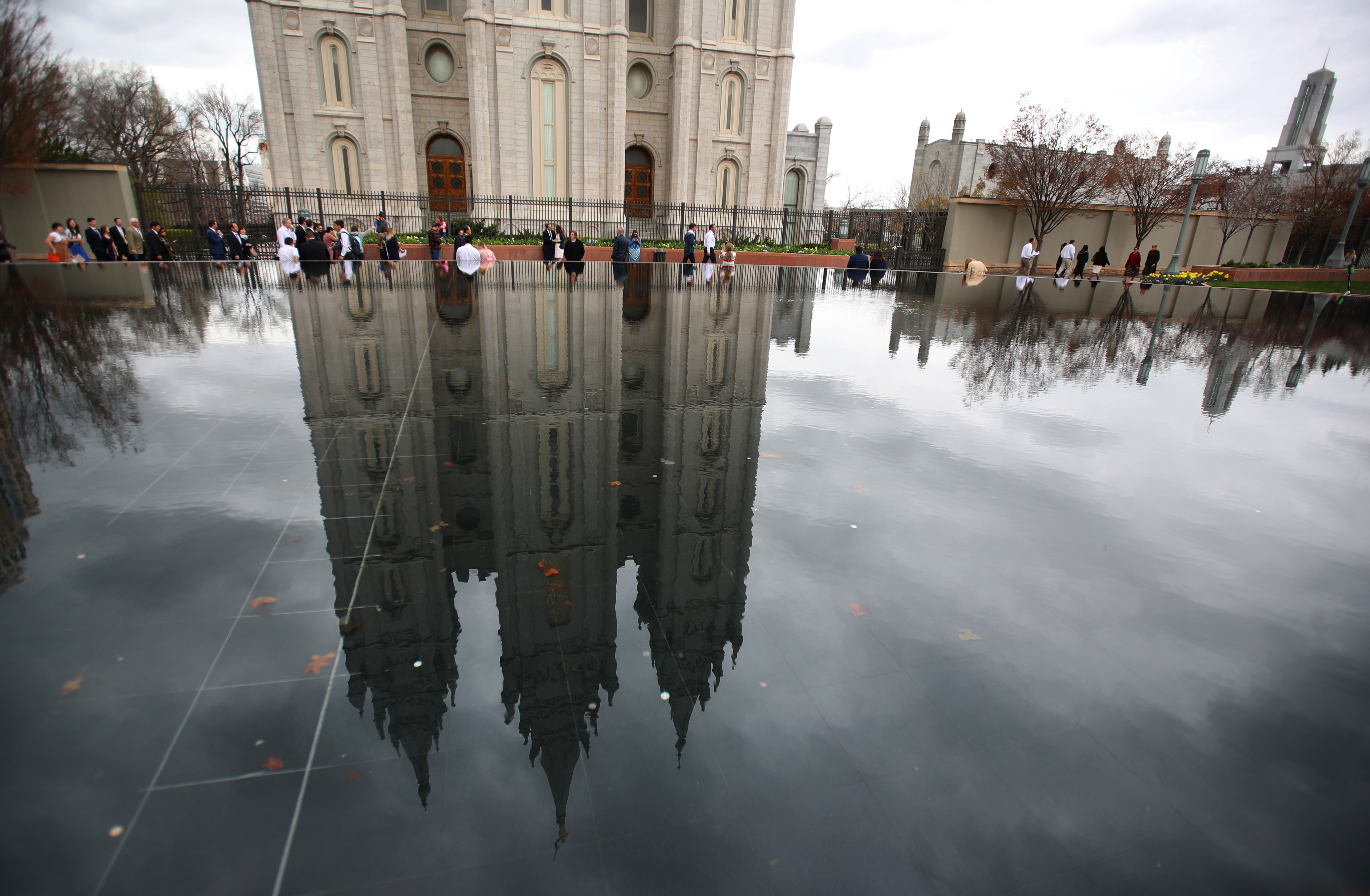 People walk past a reflection pool and the historic Salt Lake Temple of the Church of Jesus Christ of Latter-Day Saints in Salt Lake City, Utah.