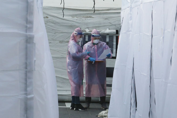 Medical staff wearing protective suits check documents as they wait for people with suspected symptoms of the novel coronavirus, at a testing facility in Seoul, on Wednesday, March 4. 