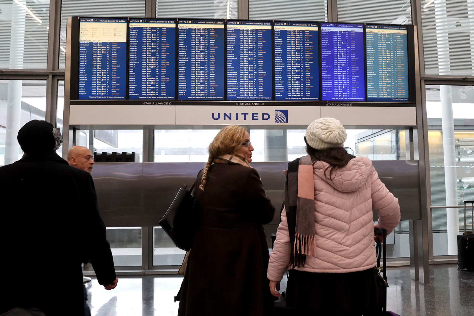 Travelers check the status of their flights at O'Hare International Airport on December 22 in Chicago.
