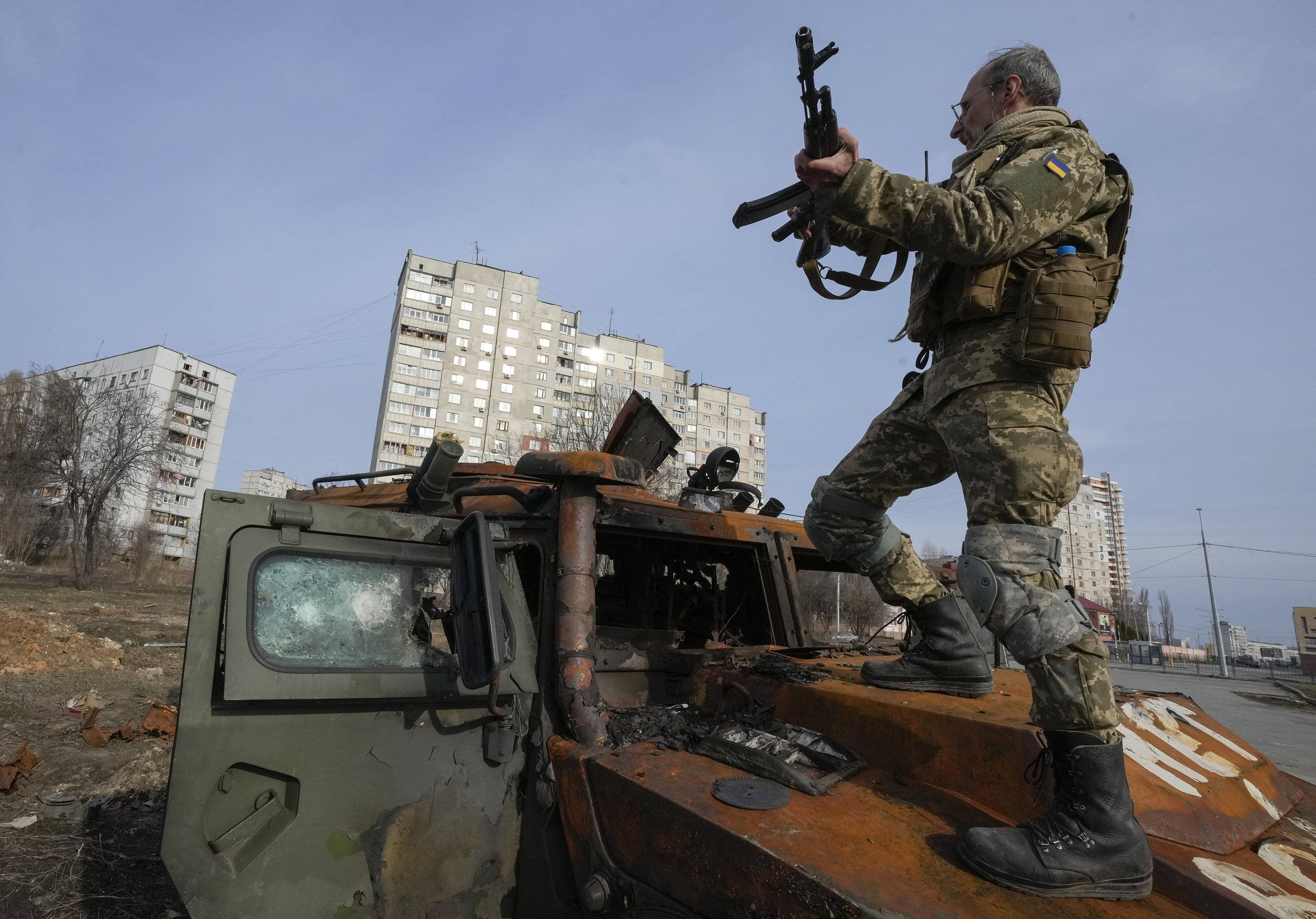 A Ukrainian soldier stands on top of a destroyed Russian armored personnel carrier after recent battle in Kharkiv, Ukraine, Saturday, March 26.