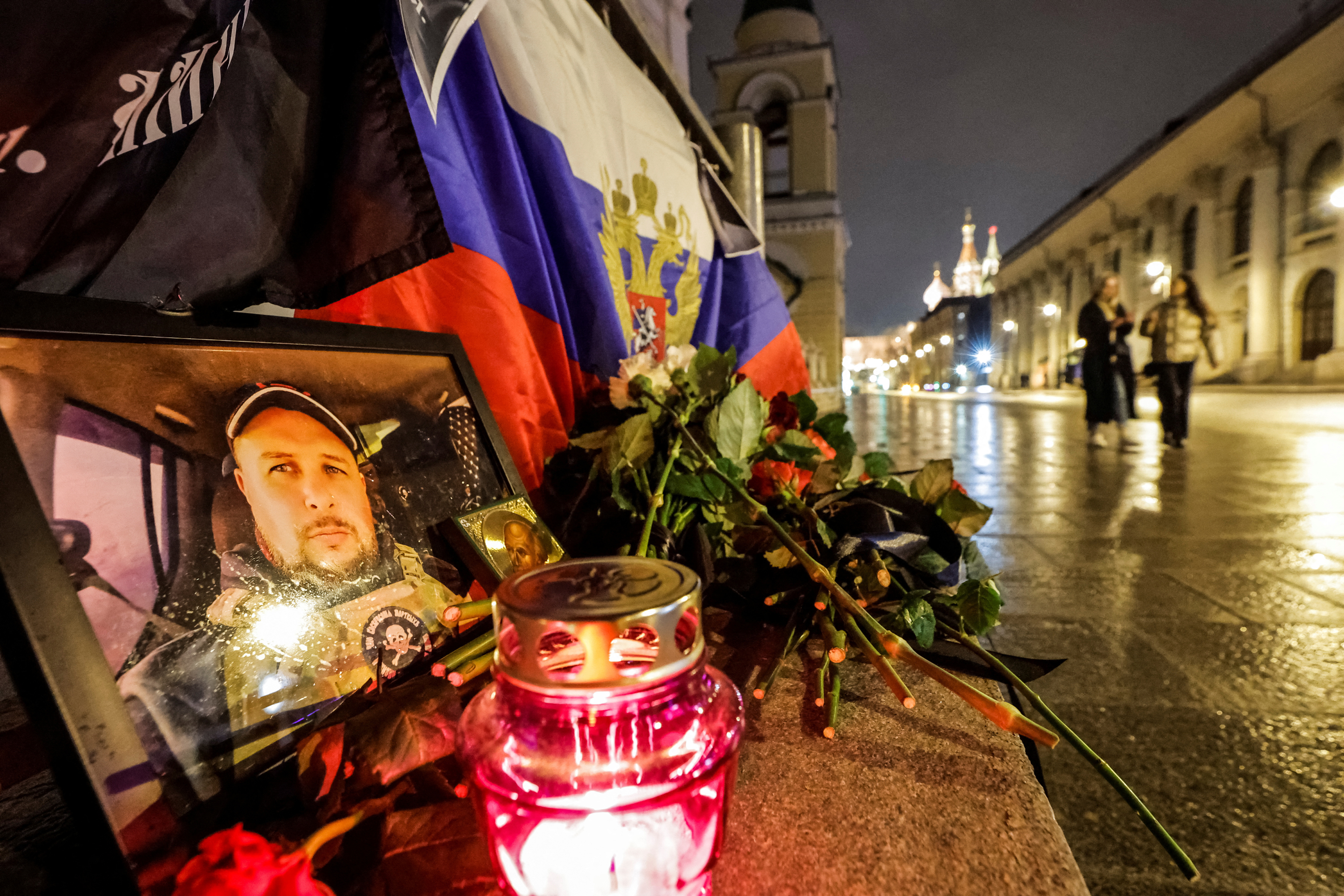 People walk past a portrait of Russian military journalist Vladen Tartovsky, who was killed in a cafe explosion in Moscow, Russia on Monday.