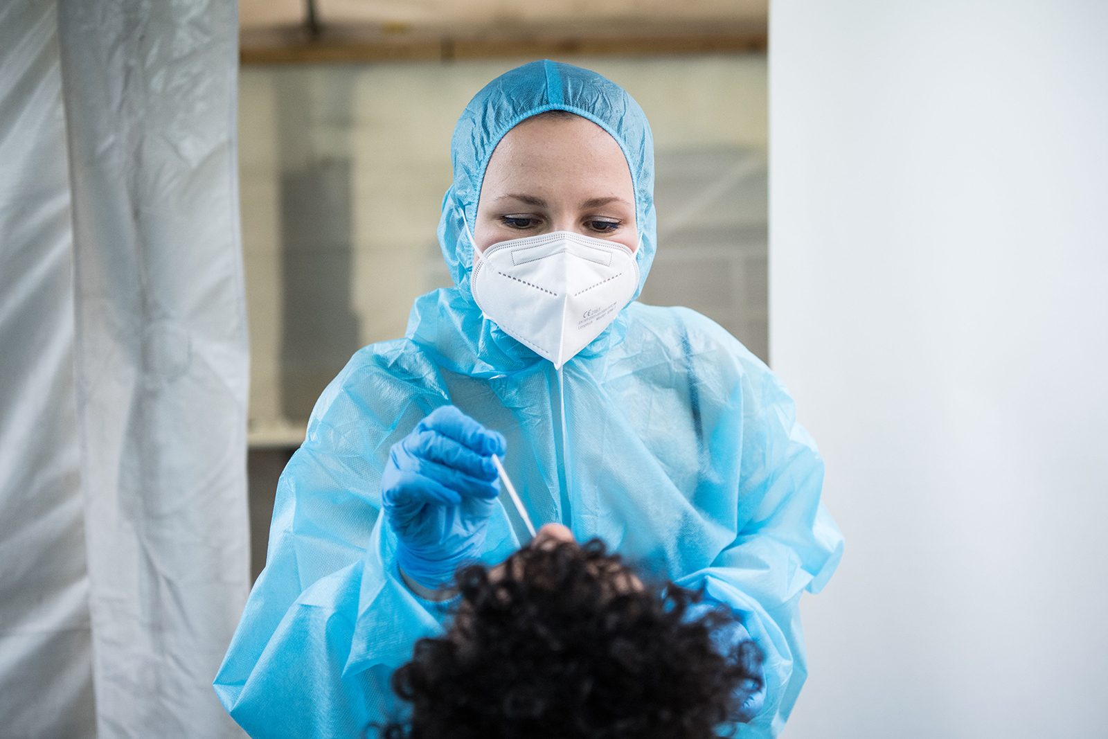 An employee wearing PPE takes a swab to test for Covid-19 on a patient at a coronavirus test center, in Berlin, on December 23.