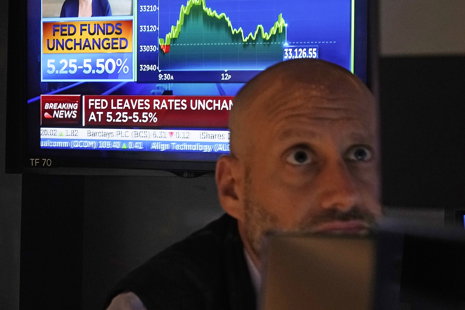 A television screen shows the rate decision of the Federal Reserve a trader works at his post on the floor of the New York Stock Exchange, Wednesday, Nov. 1.