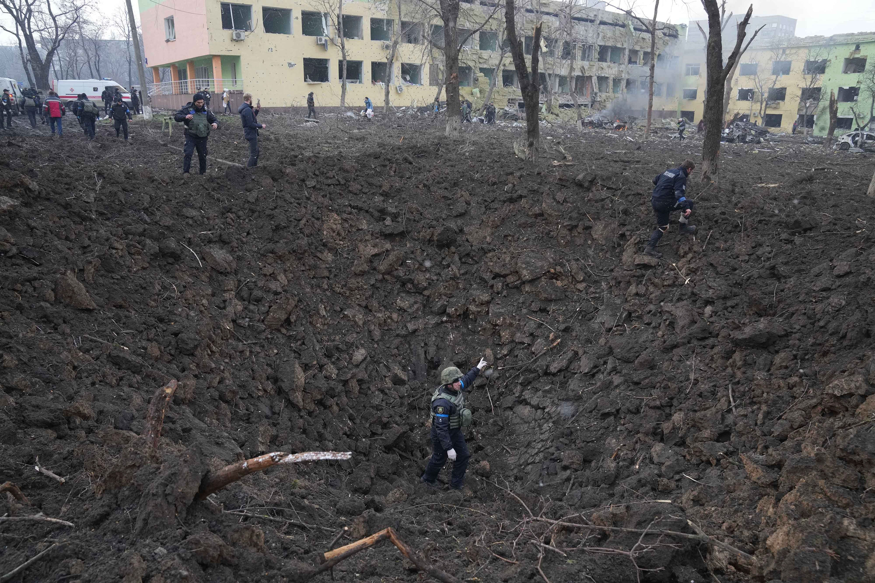 Ukrainian soldiers and emergency personnel work at the site of the shelling.