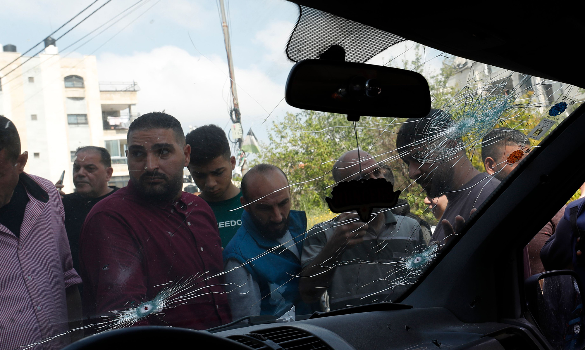 Palestinians inspect the car of a man who was injured in an Israeli raid in the West Bank city of Nablus, on April 15.