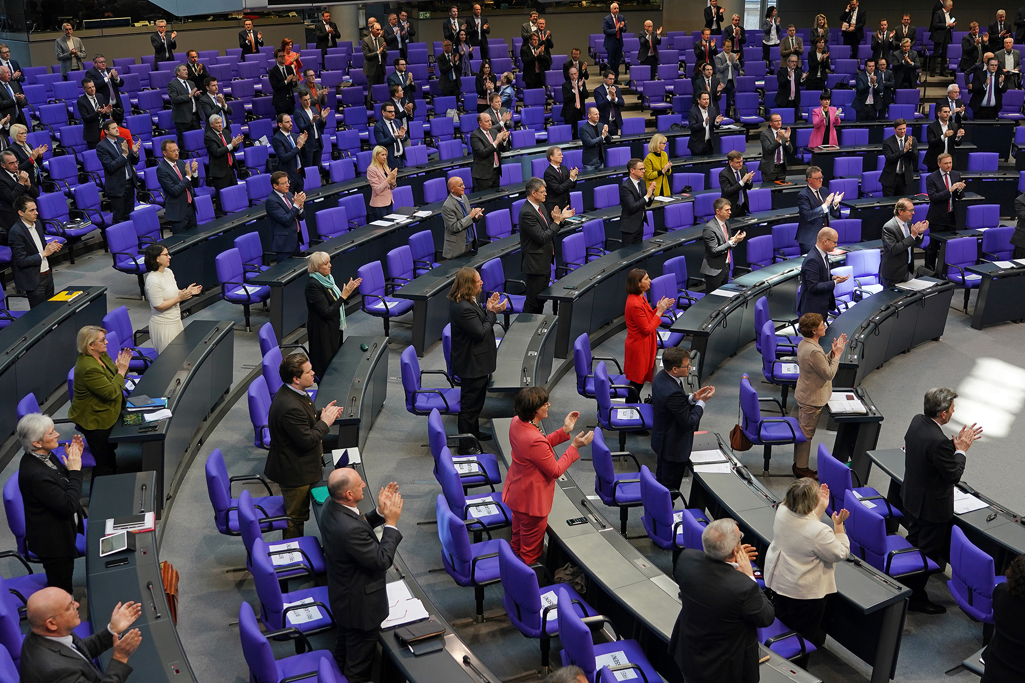 Members of the Bundestag rise to applaud medical and emergency workers on the front line of the nationwide struggle against the coronavirus prior to debates and the likely passing of a massive federal financial aid package to shore Germany up against the effects of the virus on March 25 in Berlin. 