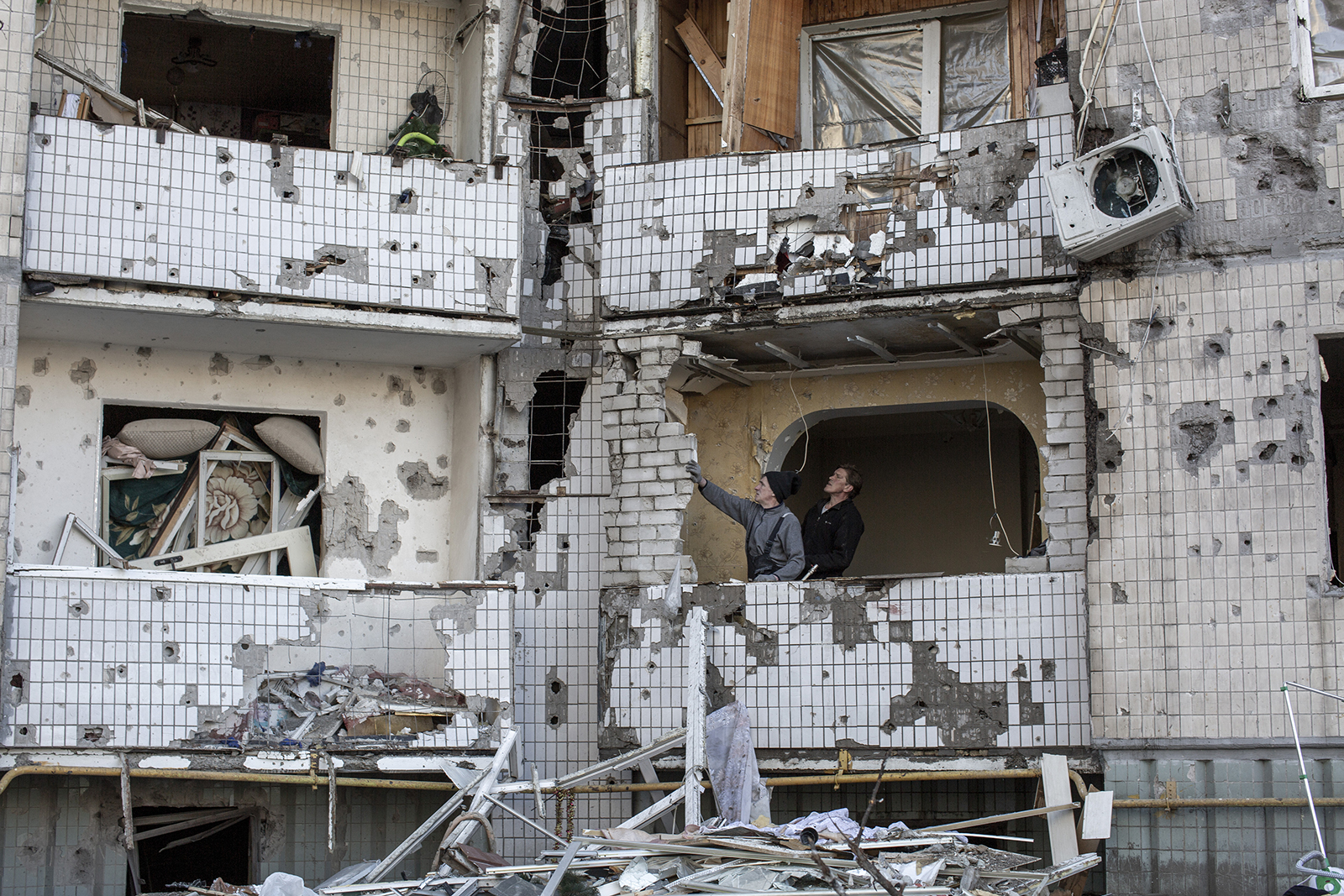 Civilians examine a residential building after it was bombed two days ago, in Kyiv on March 21. 