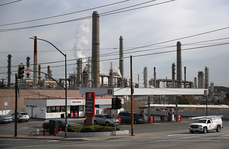 A car drives by a Speedway gas station next to a Shell refinery on March 03, 2021 in Martinez, California. 