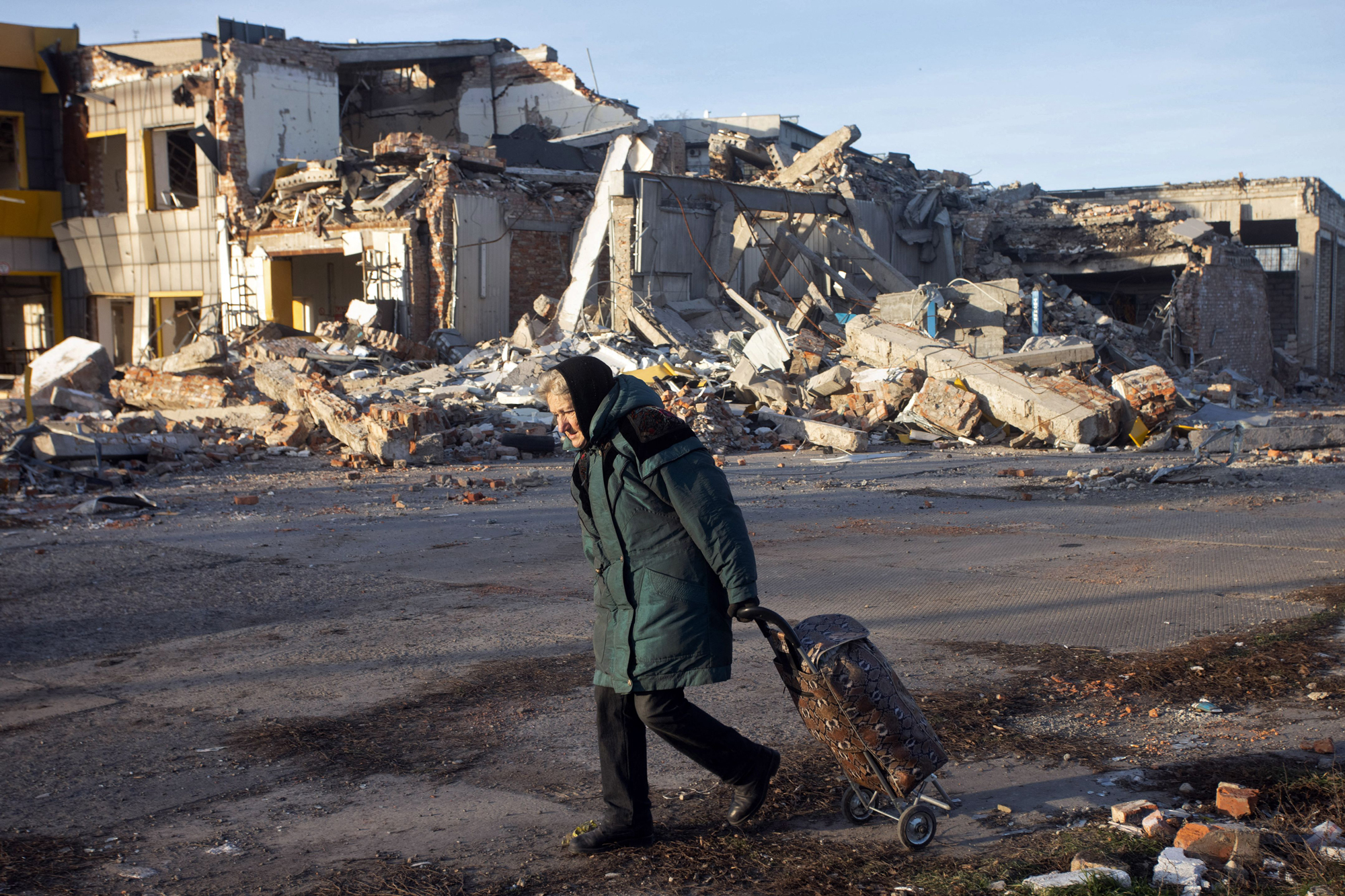 An elderly woman pulls a trolley bag past a destroyed building in Bakhmut, on Sunday.