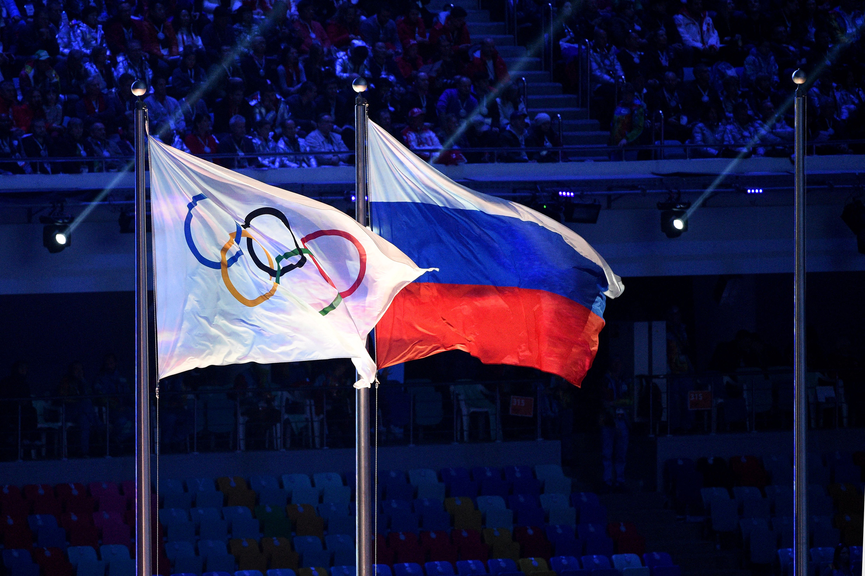 The Olympic and Russian flags fly during the closing ceremony of the Sochi Winter Olympics in Sochi, Russia in 2014.
