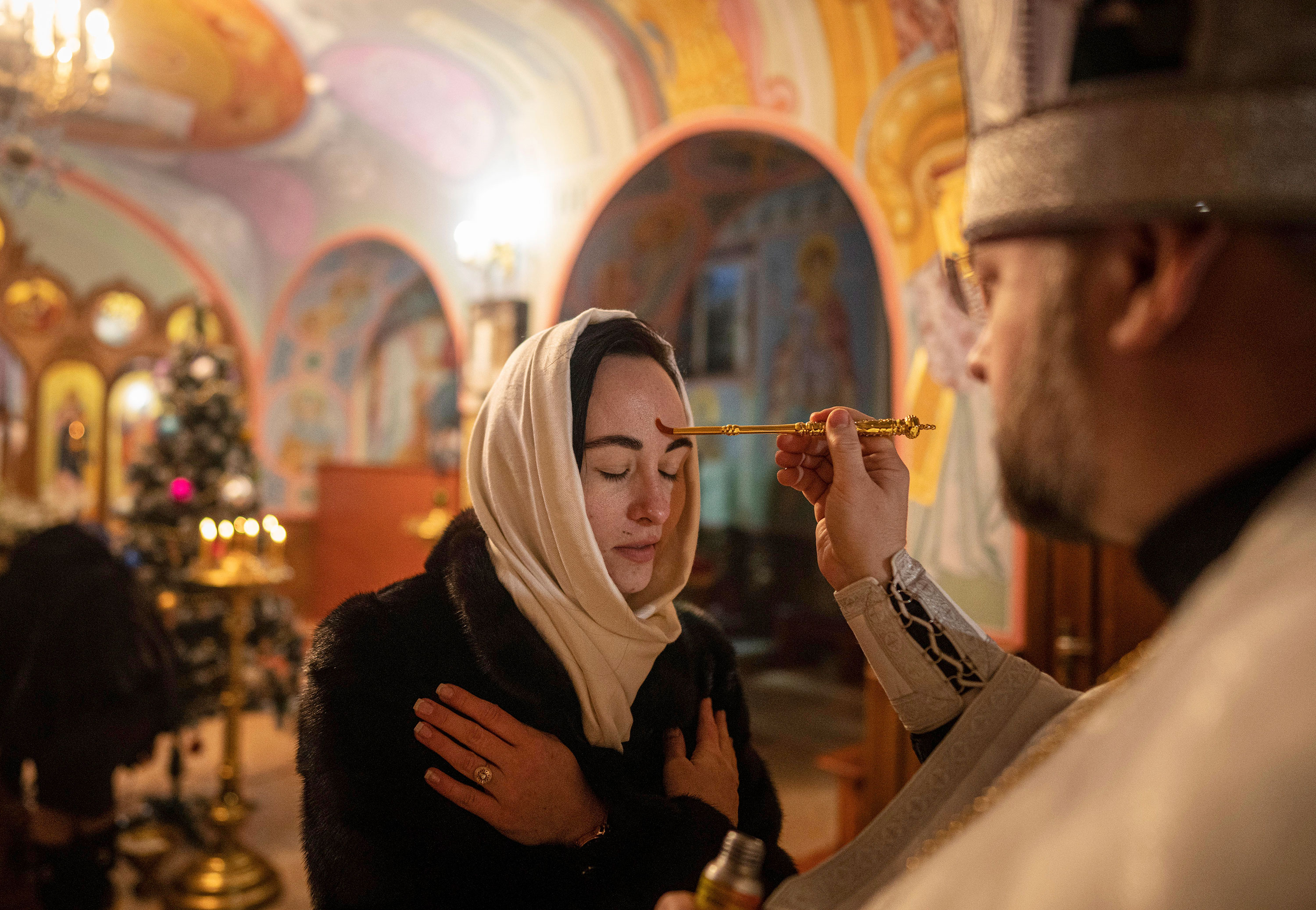 A priest offers the holy communion to a woman during Christmas service in Kostyantynivka on Friday.