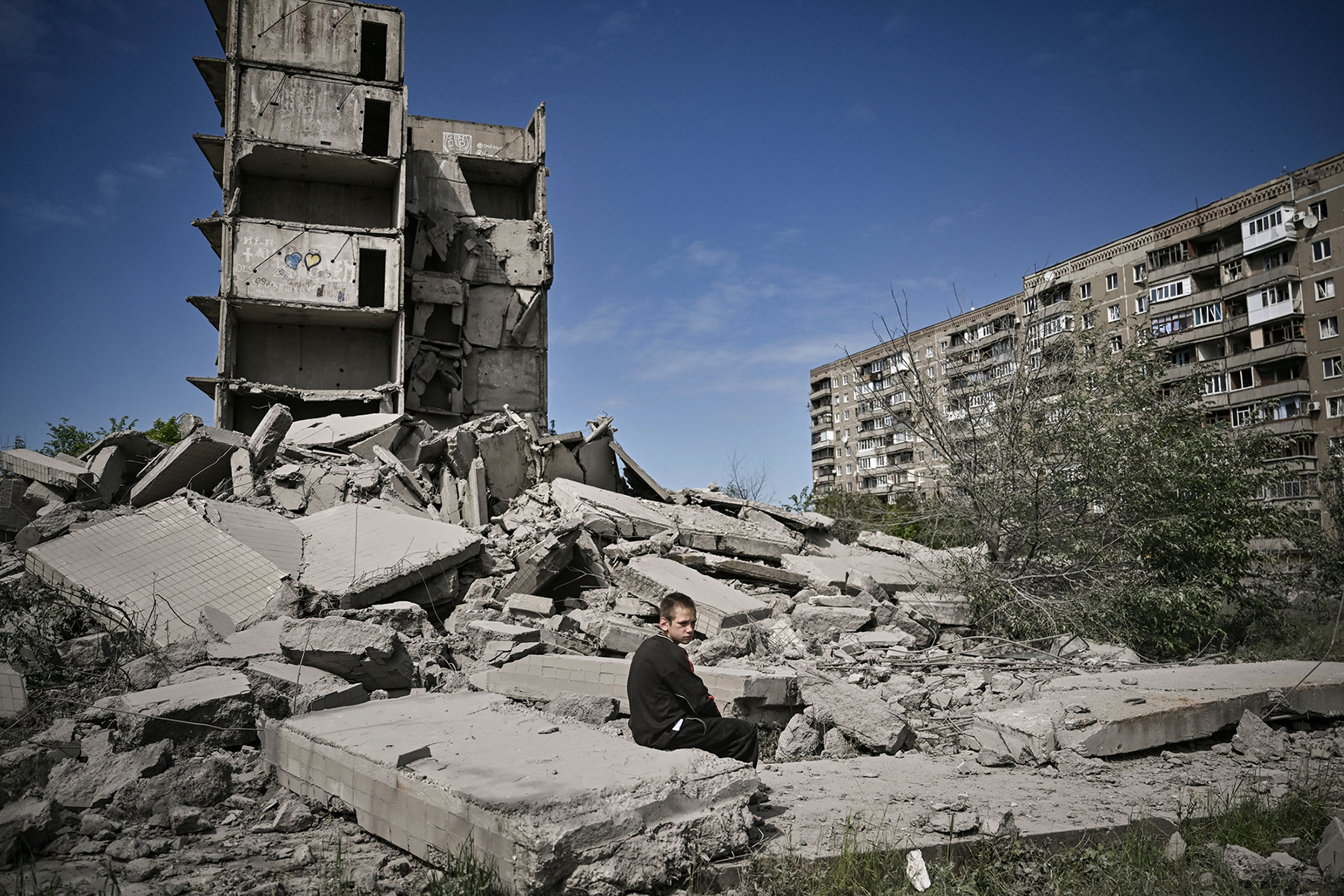 A young boy sits in front of a damaged building after a strike in Kramatorsk in the eastern Ukrainian region of Donbas, on May 25.