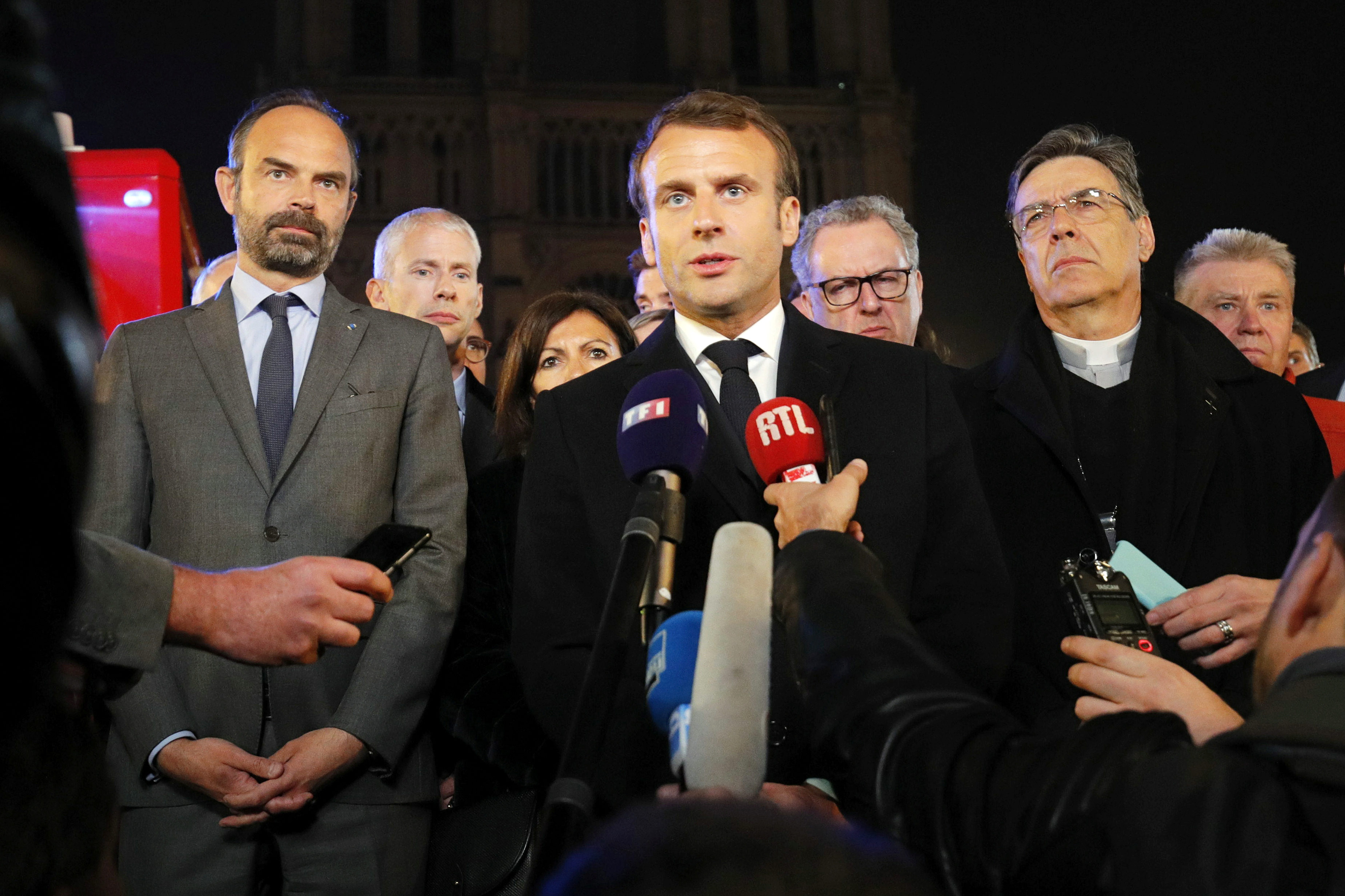 Archbishop of Paris Michel Aupetit, right, accompanies President Emmanuel Macron and other officials as he speaks outside Notre Dame Cathedral.
