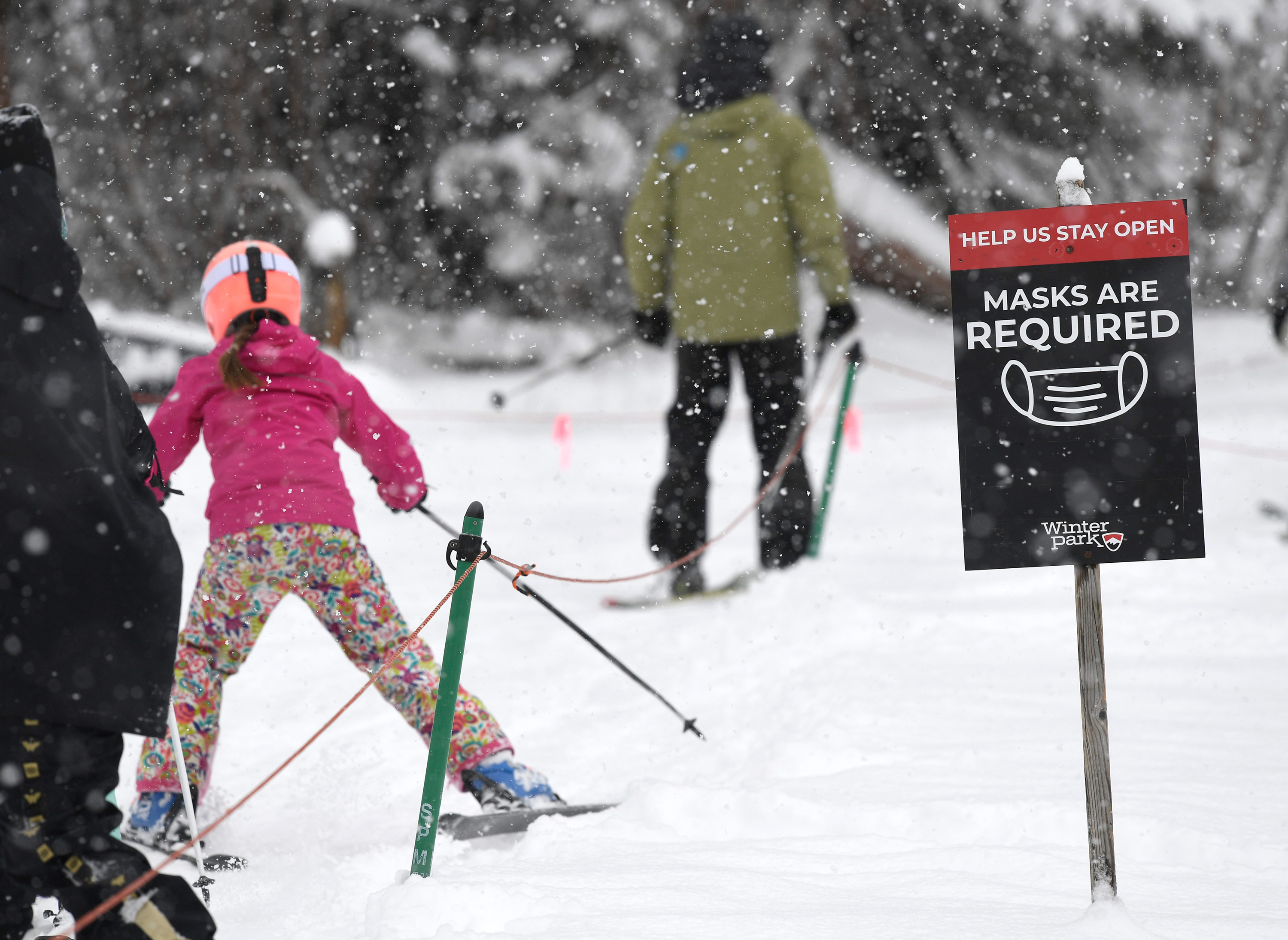 Skiers pass a mandatory face masks sign in Winter Park, Colorado, on February 13.