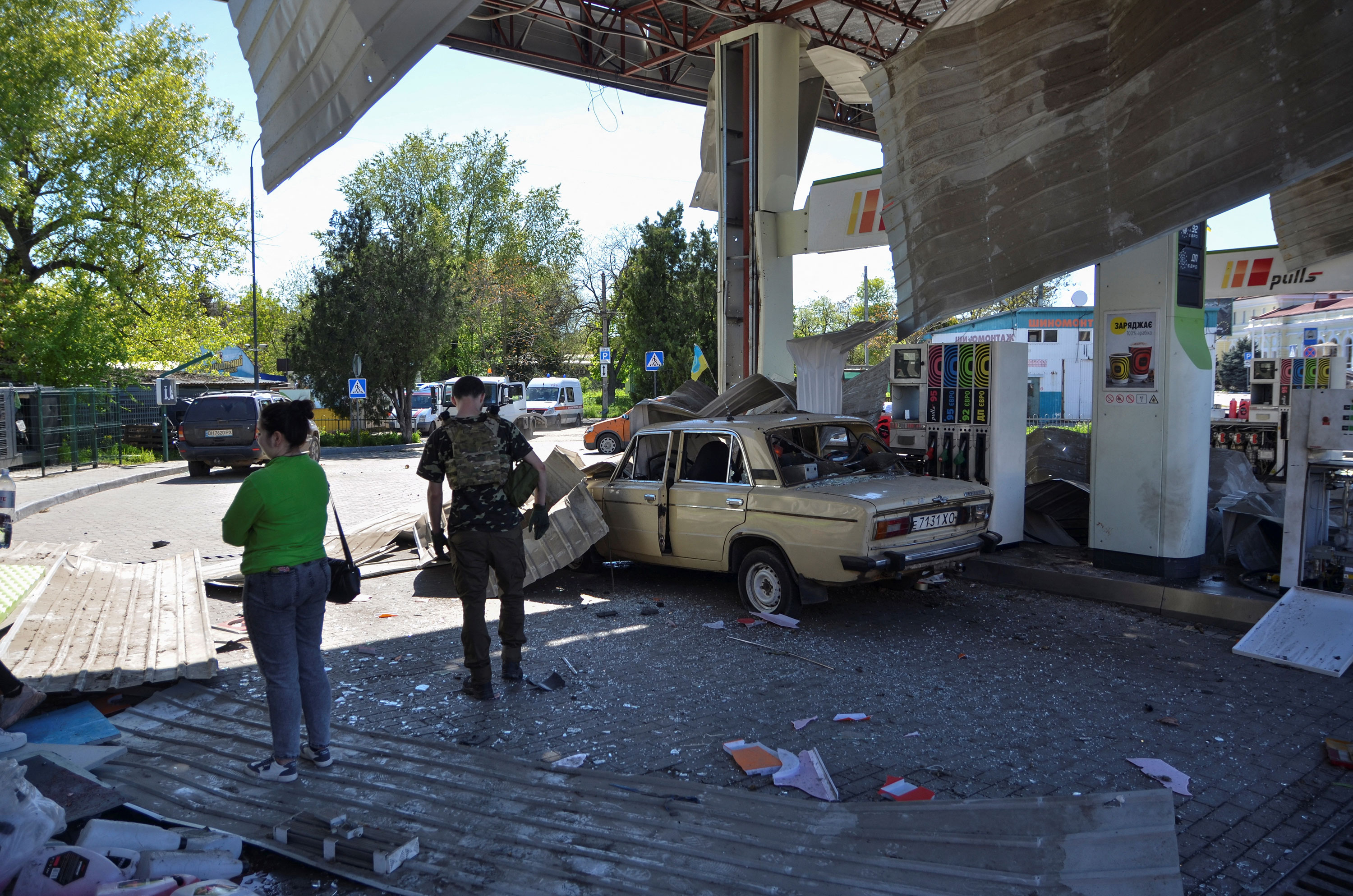People are seen at a gas station damaged by a Russian strike in Kherson, Ukraine, on Wednesday.
