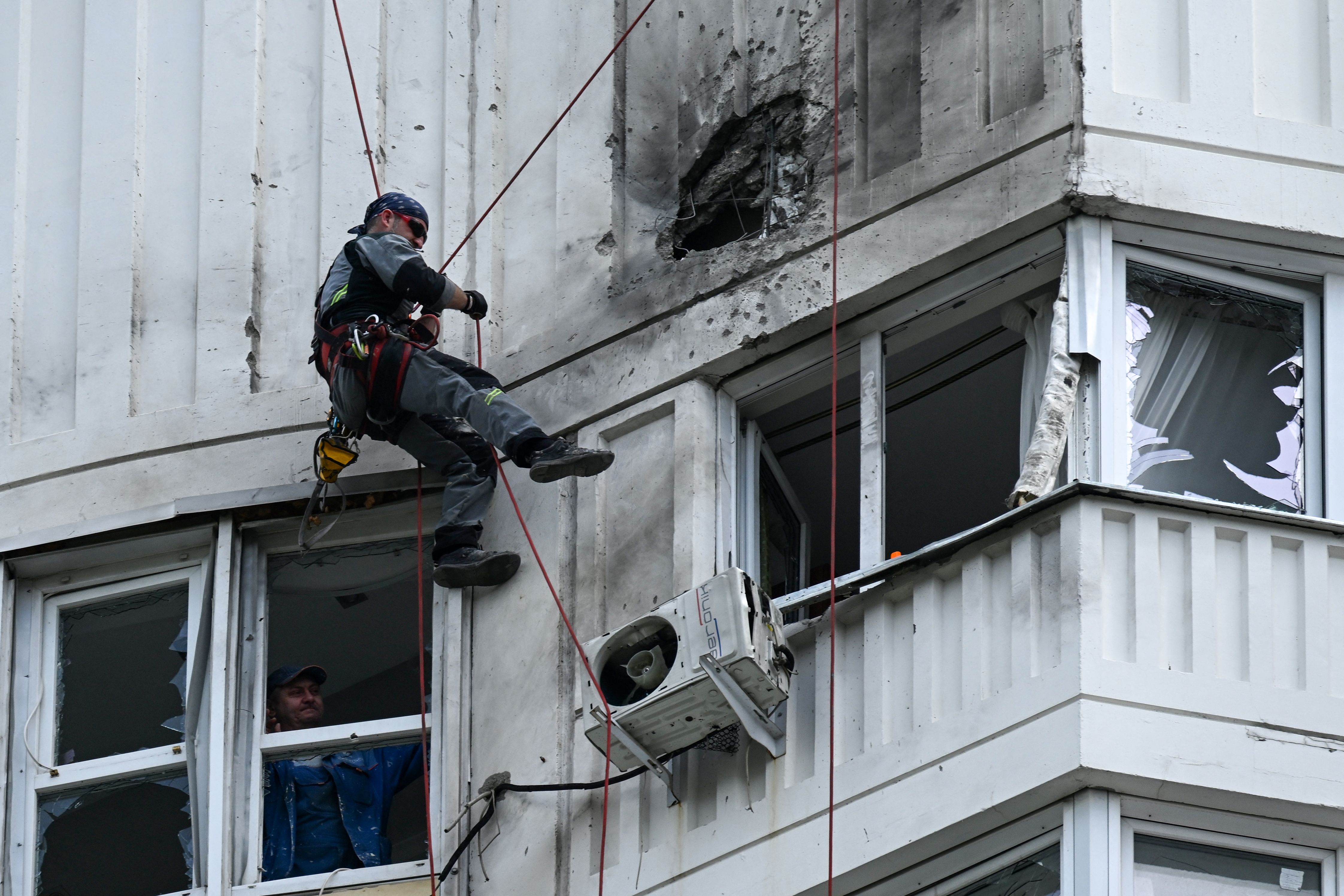 A person inspects the damaged face of an apartment building after a drone attack in Moscow on Tuesday.