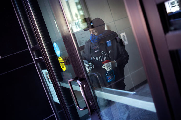 A worker disinfects the front doors of the School Without Walls High School, which was closed after a member of the school's staff reported close contact with a person who tested positive for coronavirus, on March 9, in Washington, DC. 