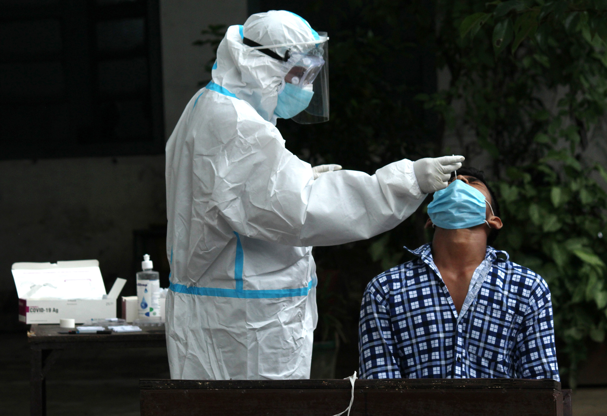 A health worker in personal protective equipment (PPE) collects a swab sample from a patient for COVID-19 Rapid Antigen Testing, on Friday, September 4, in New Delhi, India. 