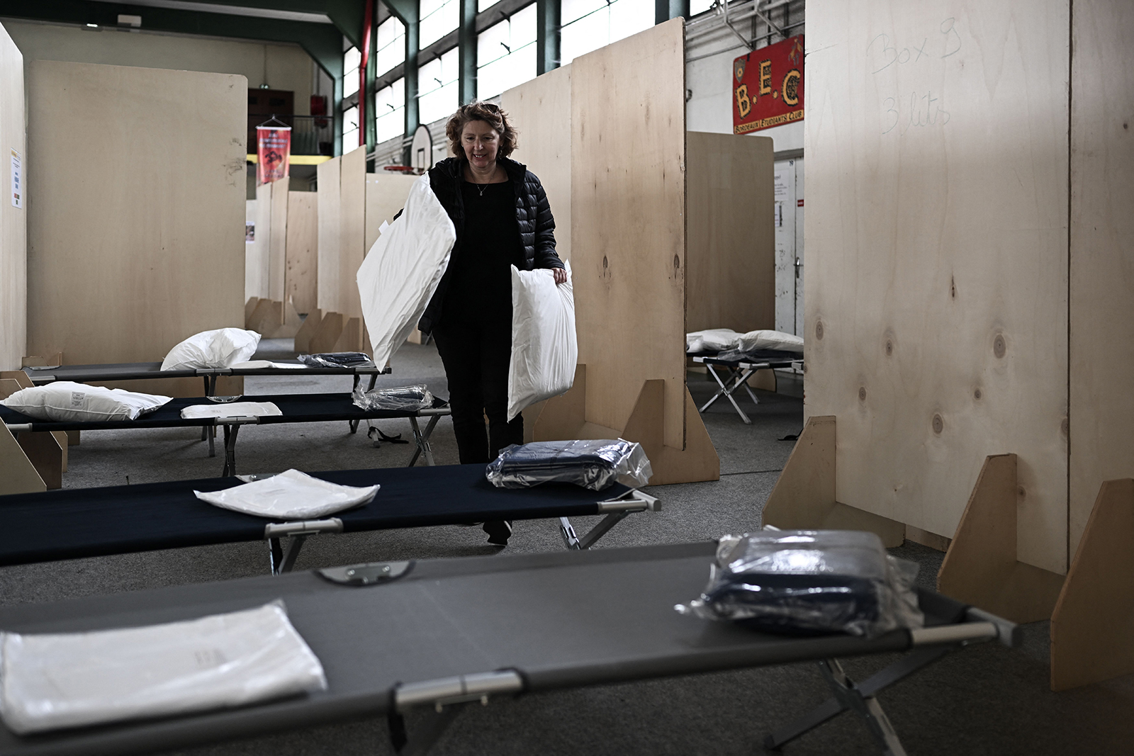 A woman places pillows on beds in a public gymnasium being prepared for Ukrainian refugees in Bordeaux, southwestern France, on March 25.