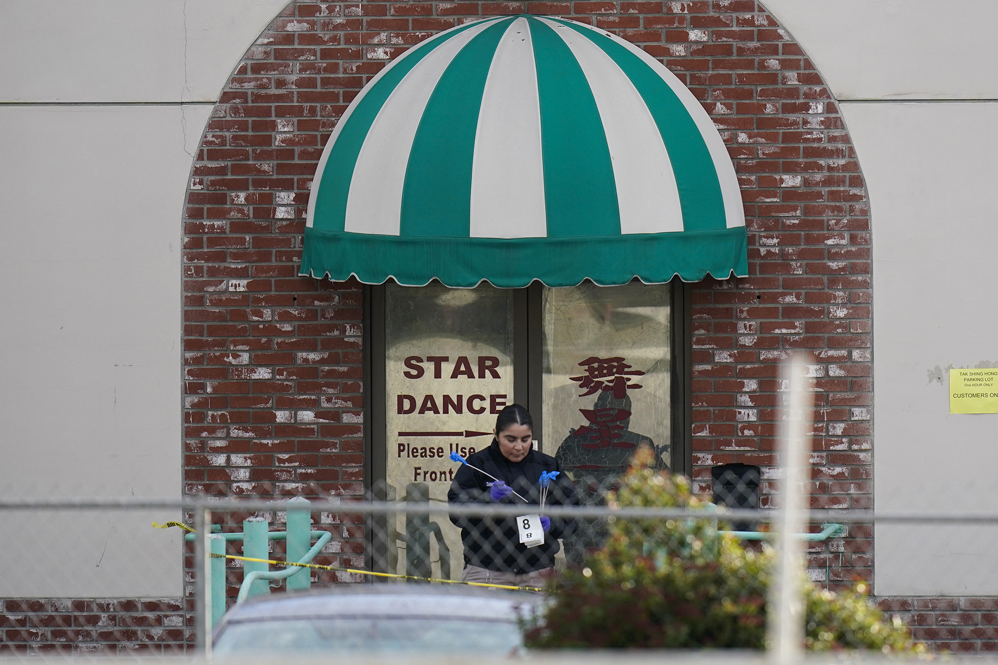 An investigator carries markers outside Star Dance Studio in Monterey Park, California on Sunday.
