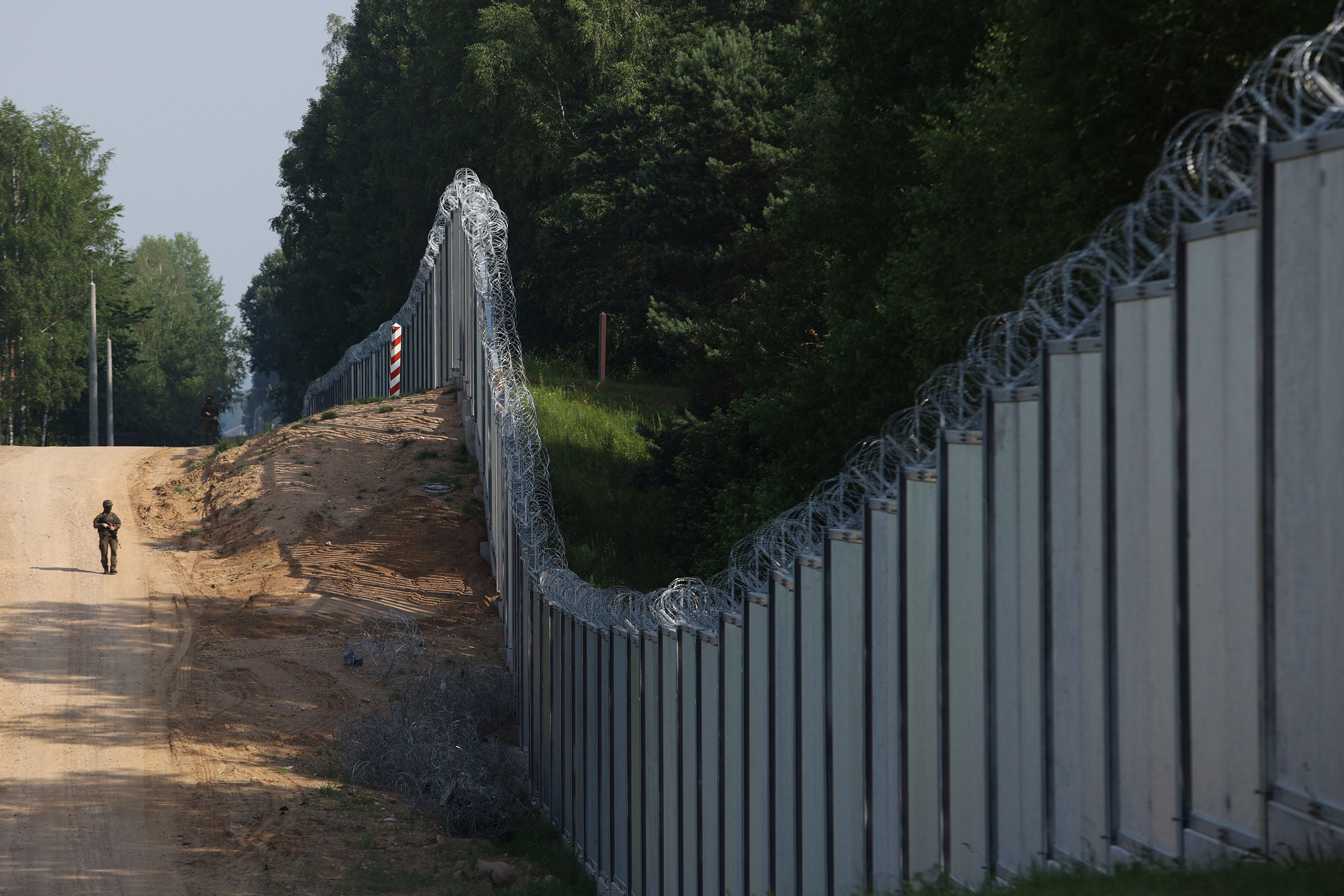 A Polish border guard patrols a metal wall on the border between Poland and Belarus, near Kuznice, Poland, on June 30, 2022. 