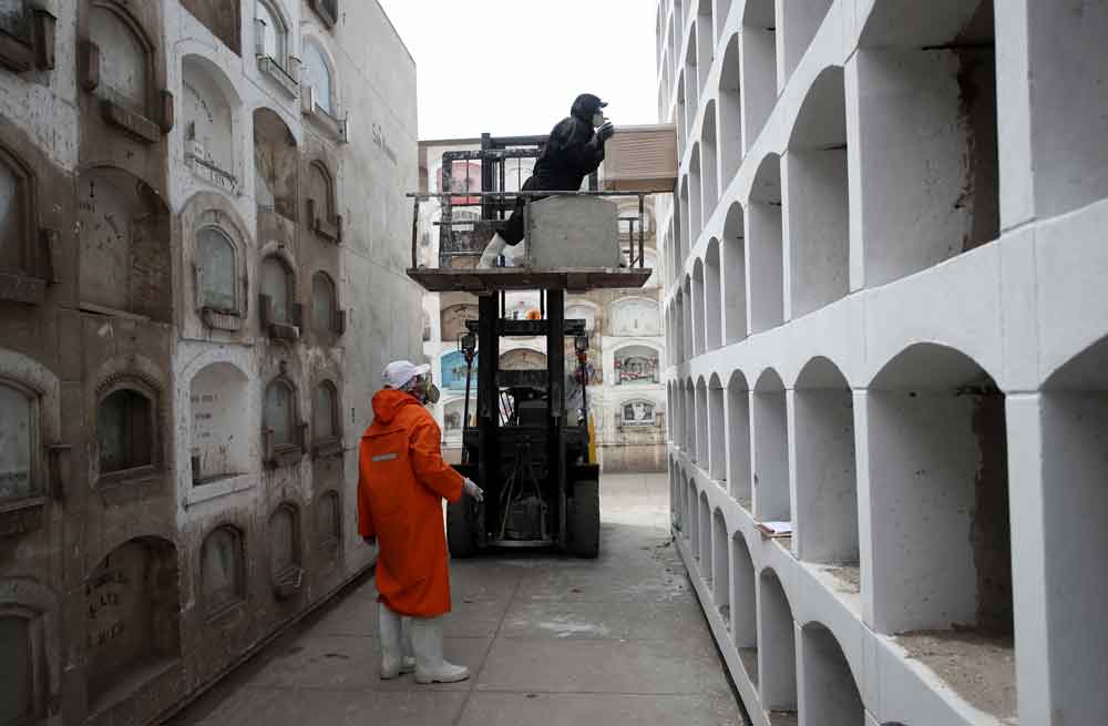 A cemetery worker pushes a coffin into a niche on June 4 in Lima, Peru.