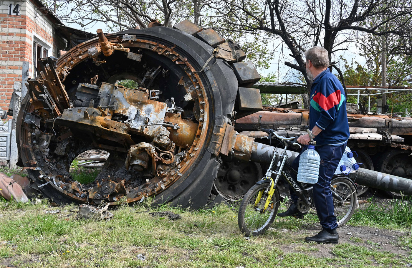  A local resident looks at a destroyed Russian tank next to a house in the village of Mala Rogan, east of Kharkiv, on May 15.