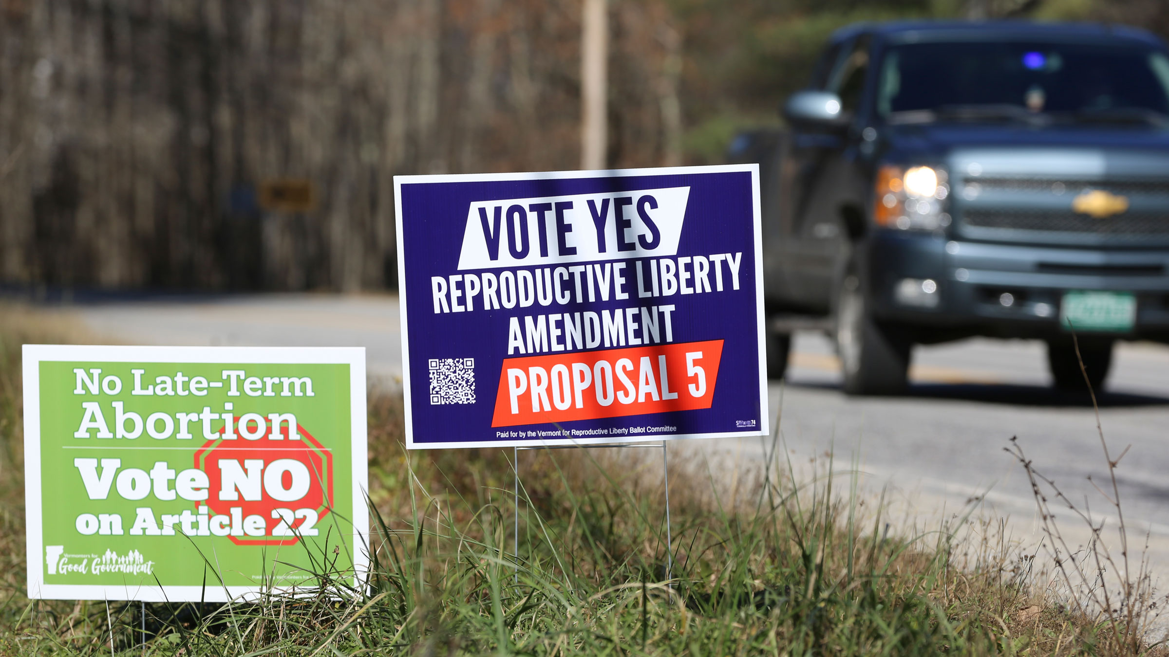 A truck in Middlesex, Vermont. drives by campaign signs opposing and supporting the proposed amendment to the Vermont constitution that would guarantee access to reproductive rights.