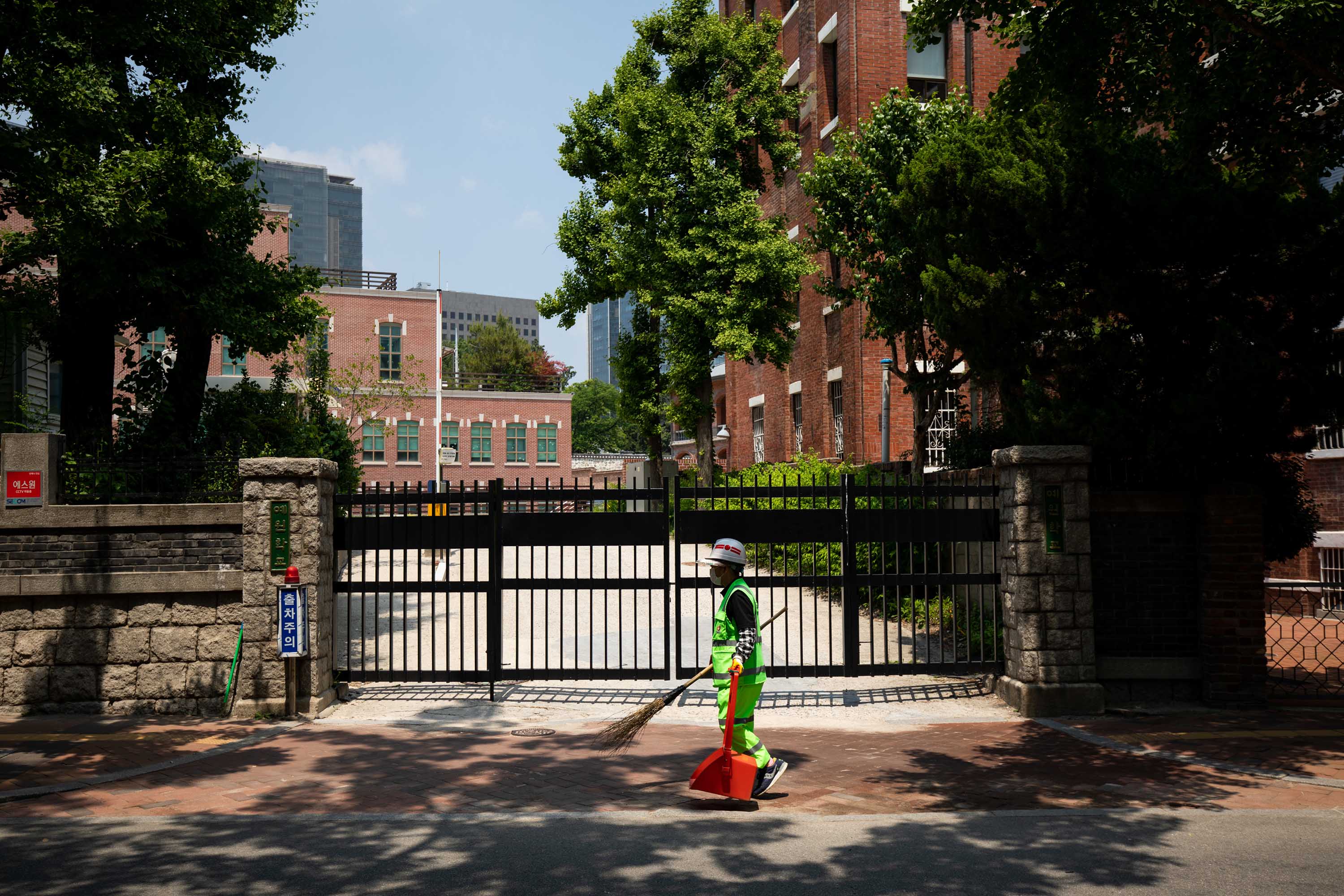 A cleaner wearing a protective mask walks past a high school in Seoul, South Korea, on Friday, May 29.